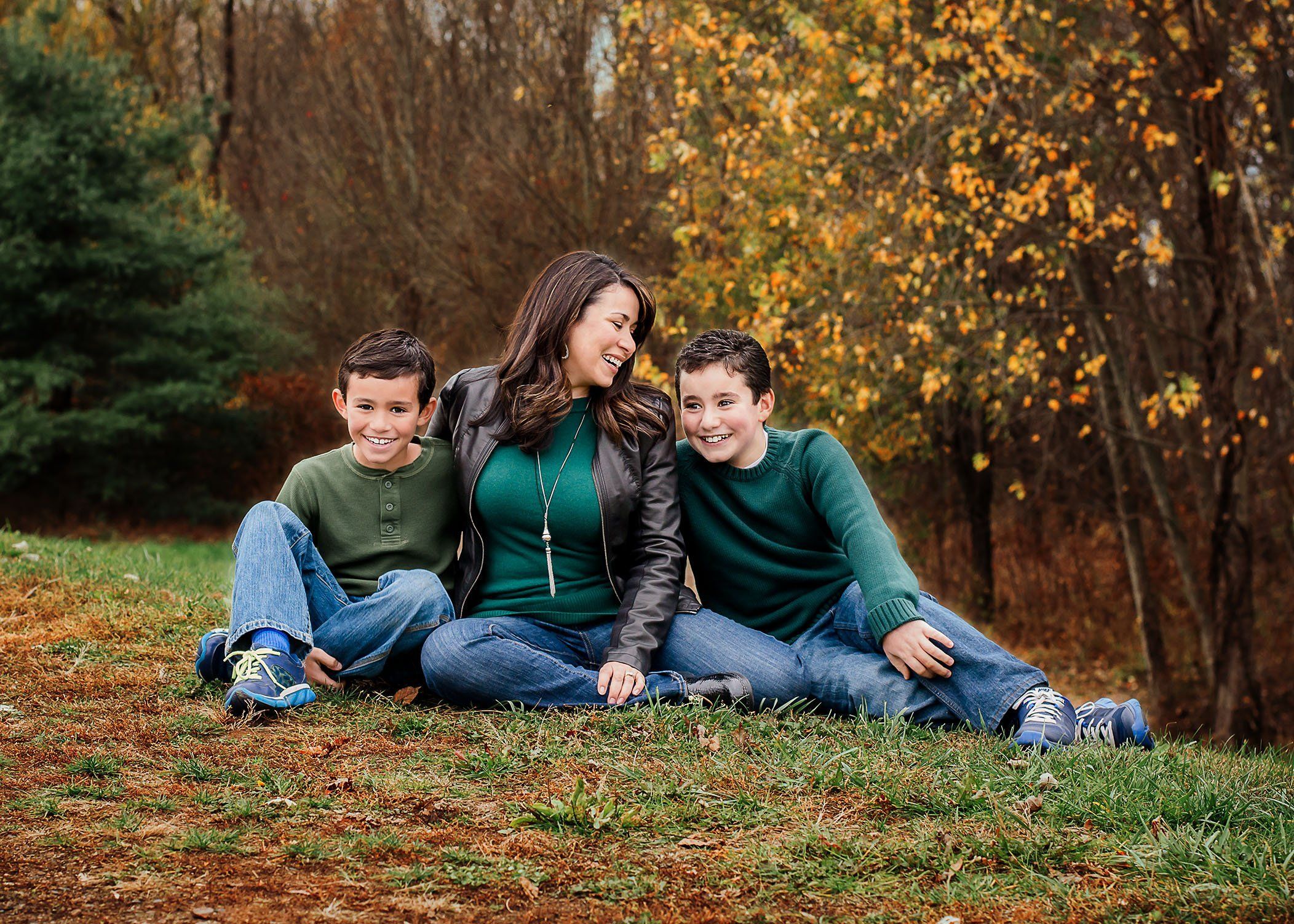 Mom and two sons sitting outside in fall laughing together