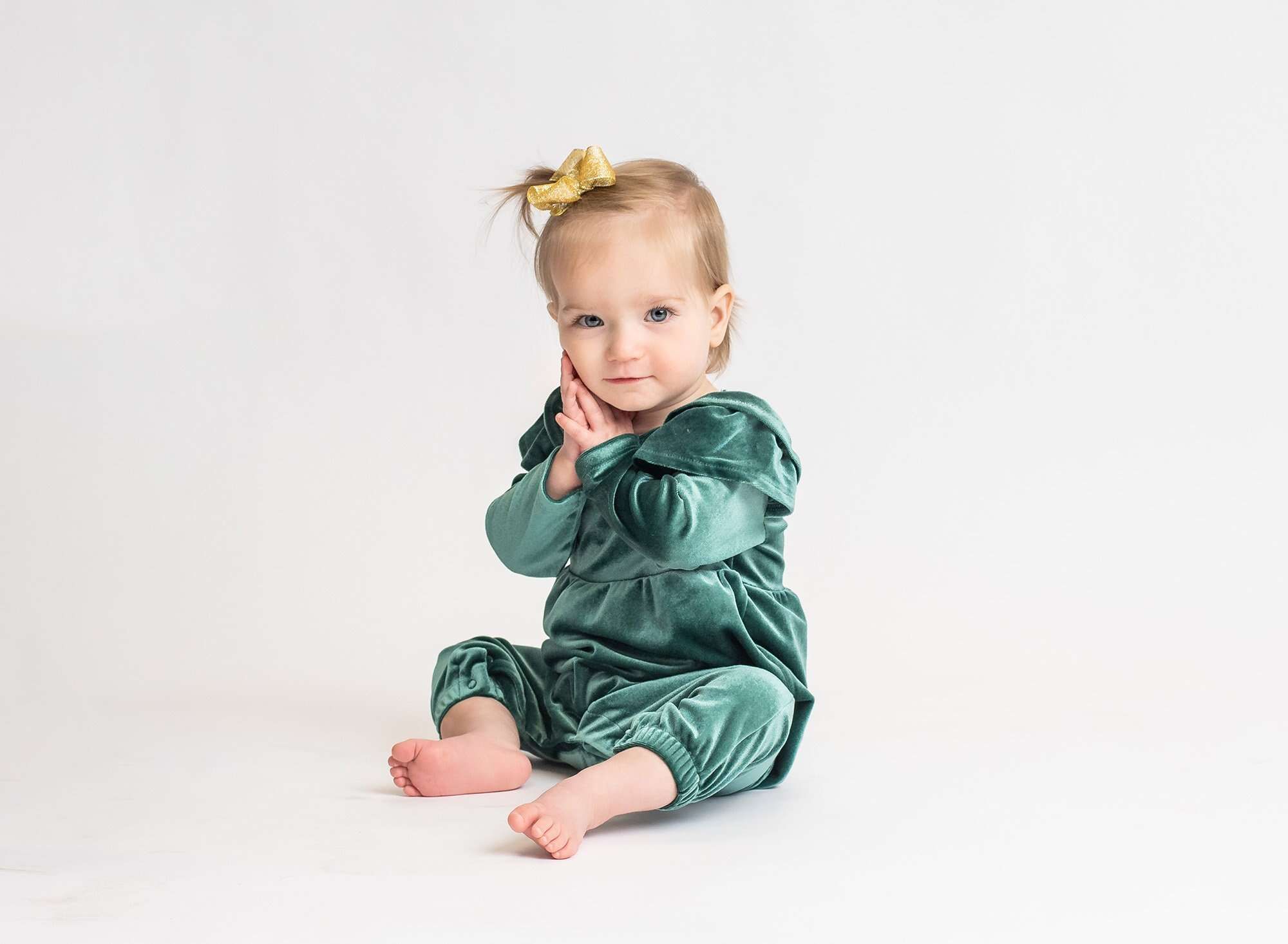little girl looking at the camera wearing green with a white background
