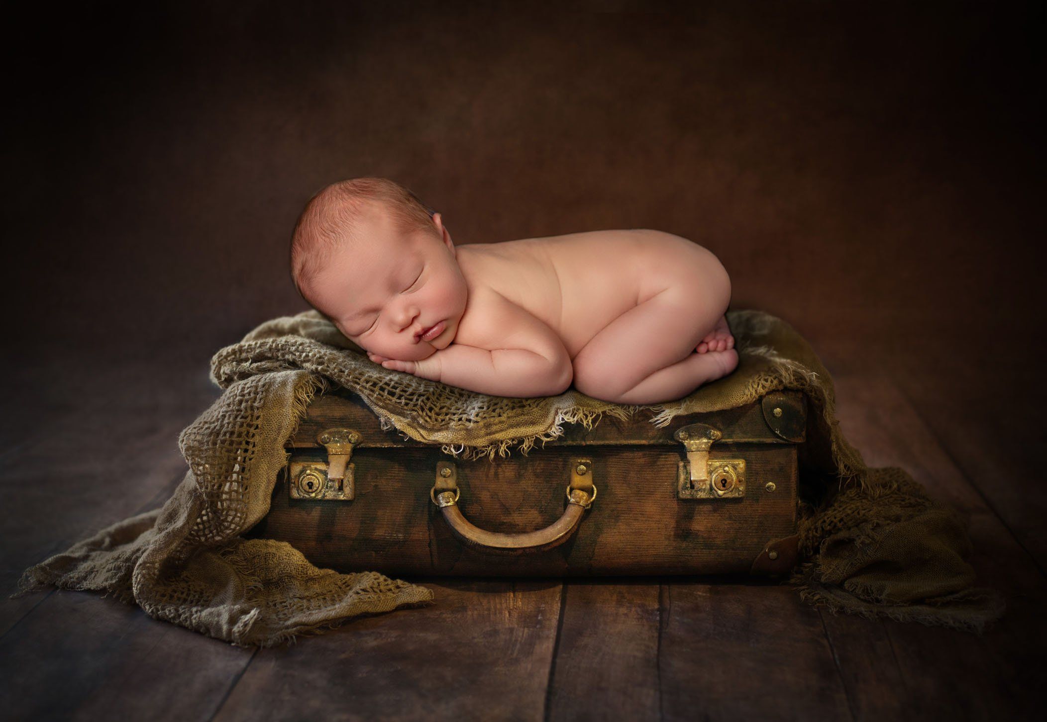baby boy sleeping on a old leather suitcase