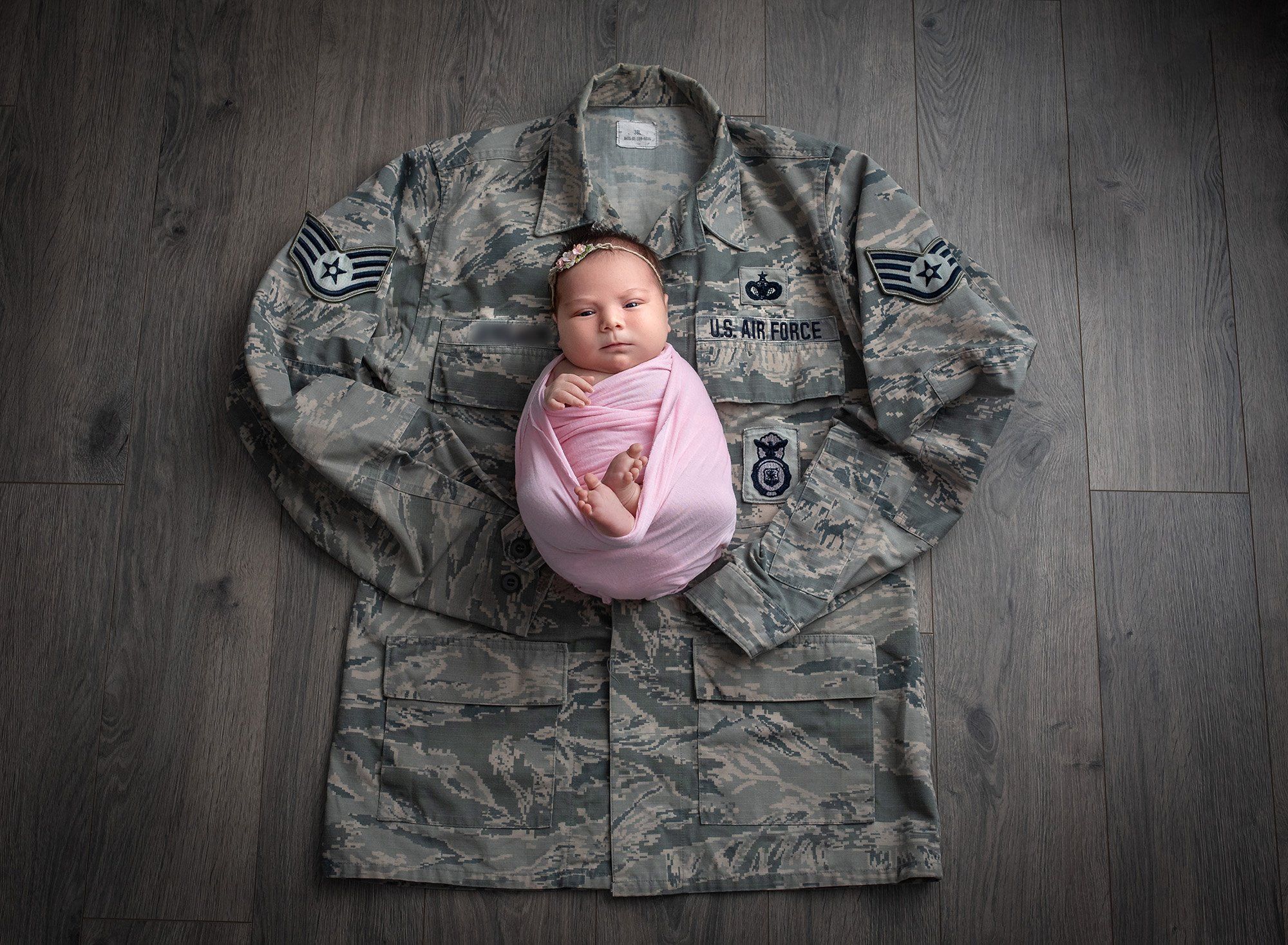 newborn baby girl swaddled on top of her deployed dad's Air Force uniform