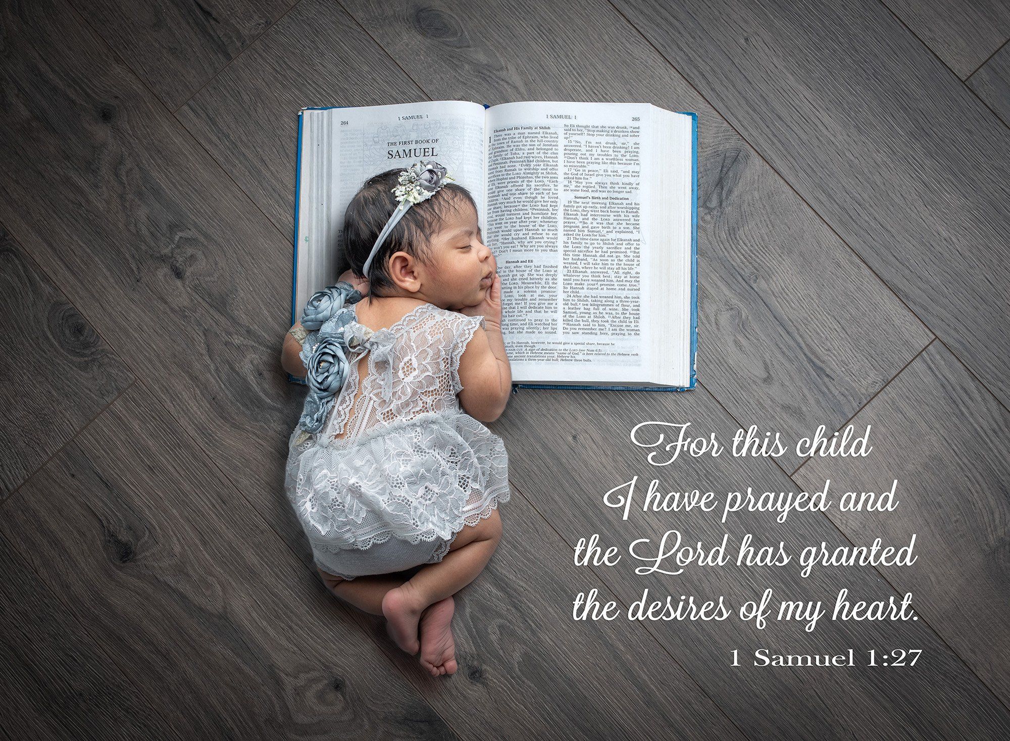 newborn baby girl dressed in floral lace grey dress sound asleep with her head on the Bible including bible quote on wooden background