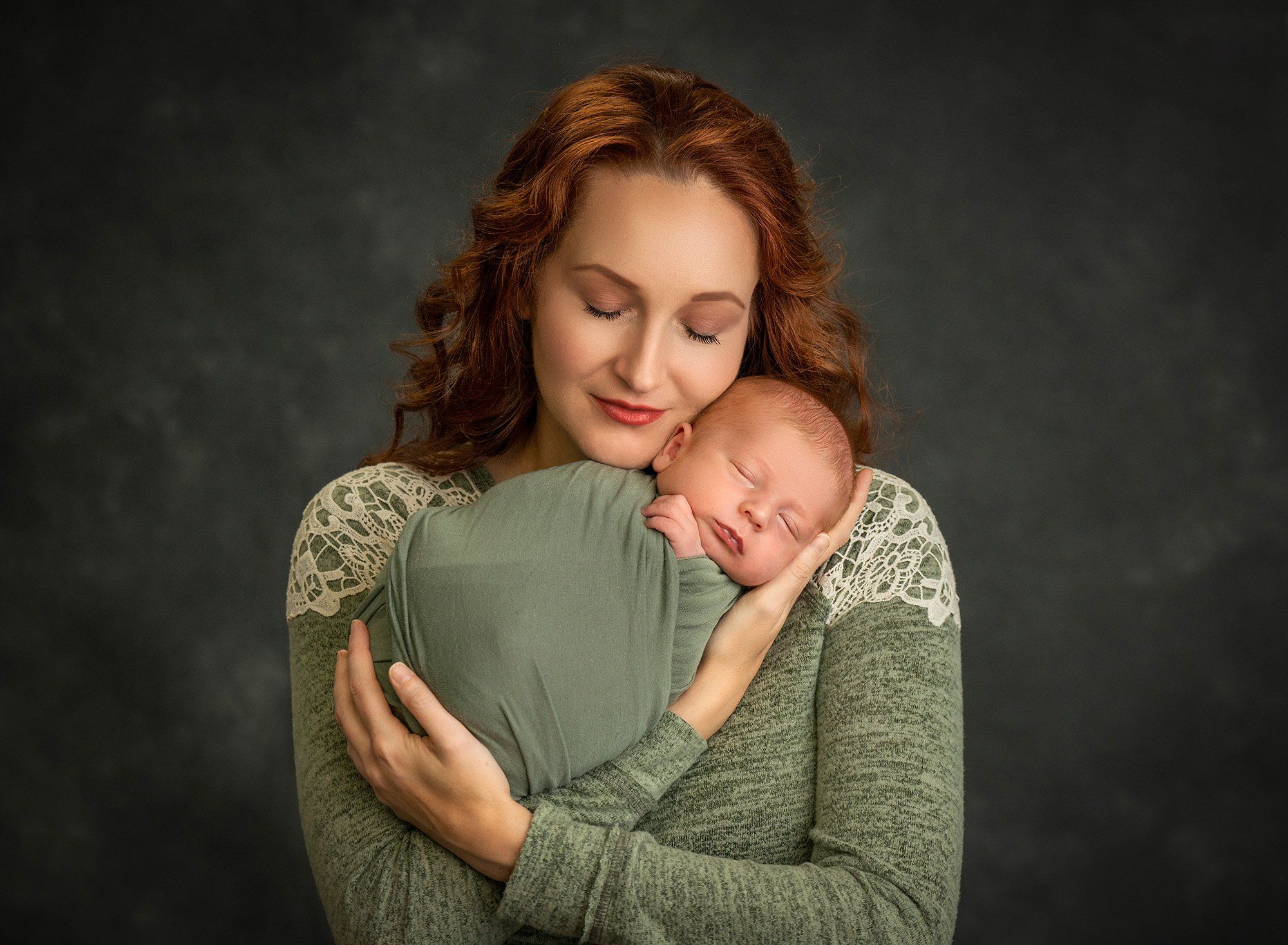 mom cradling newborn baby boy swaddled in green