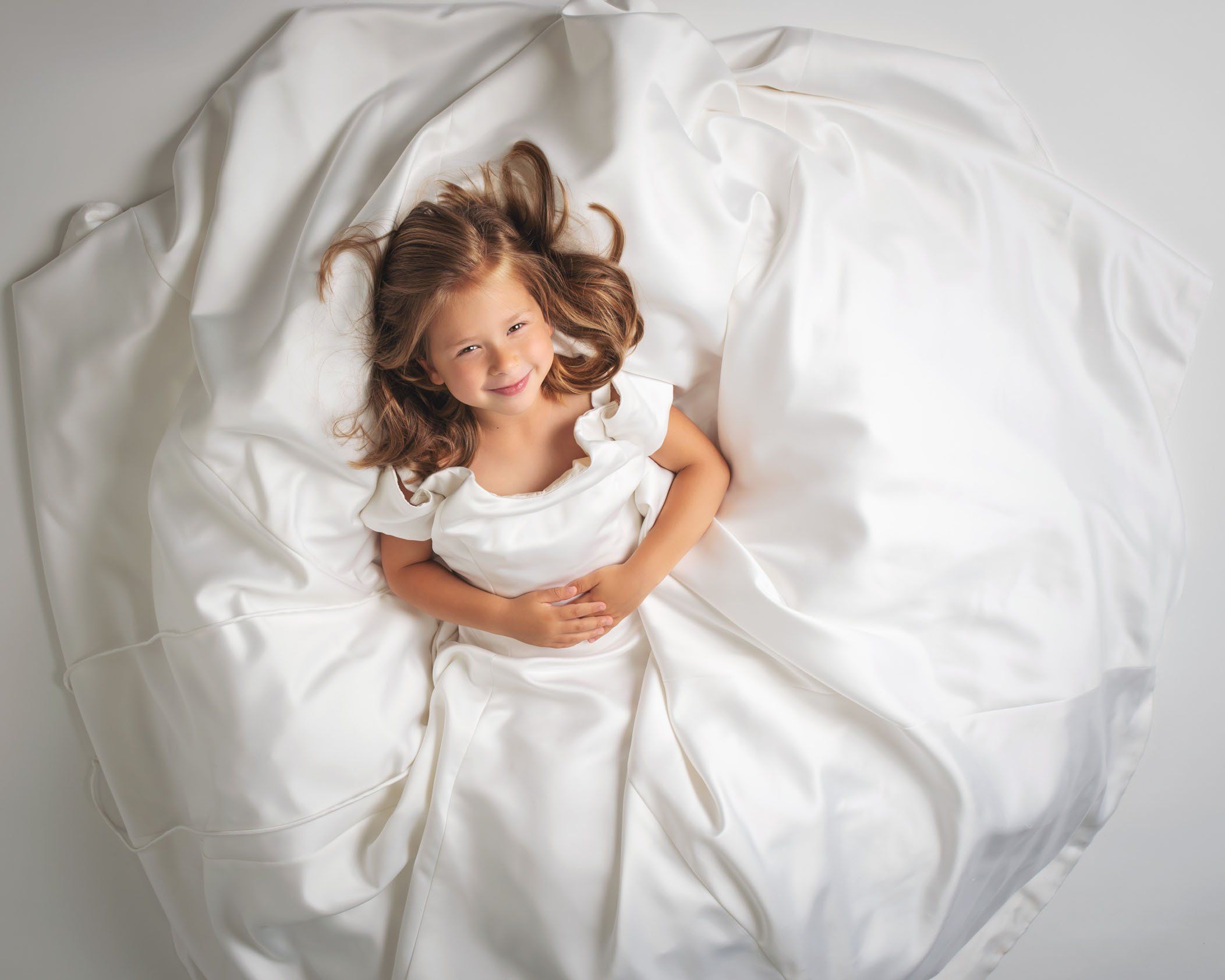5 year old girl lying on the floor in her mom's wedding dress