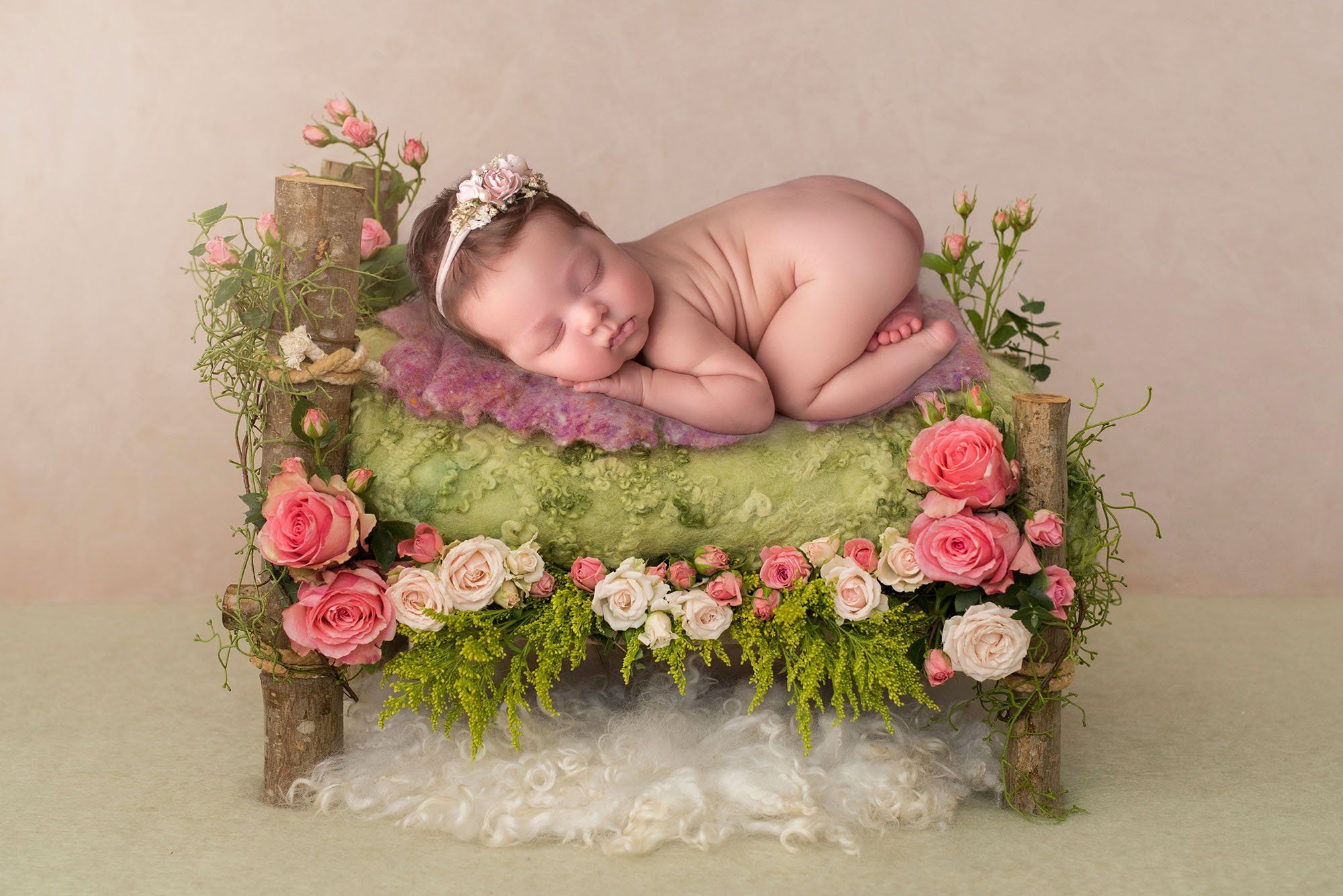 sleeping newborn girl on a rustic wooden bed with roses best time to take newborn photos