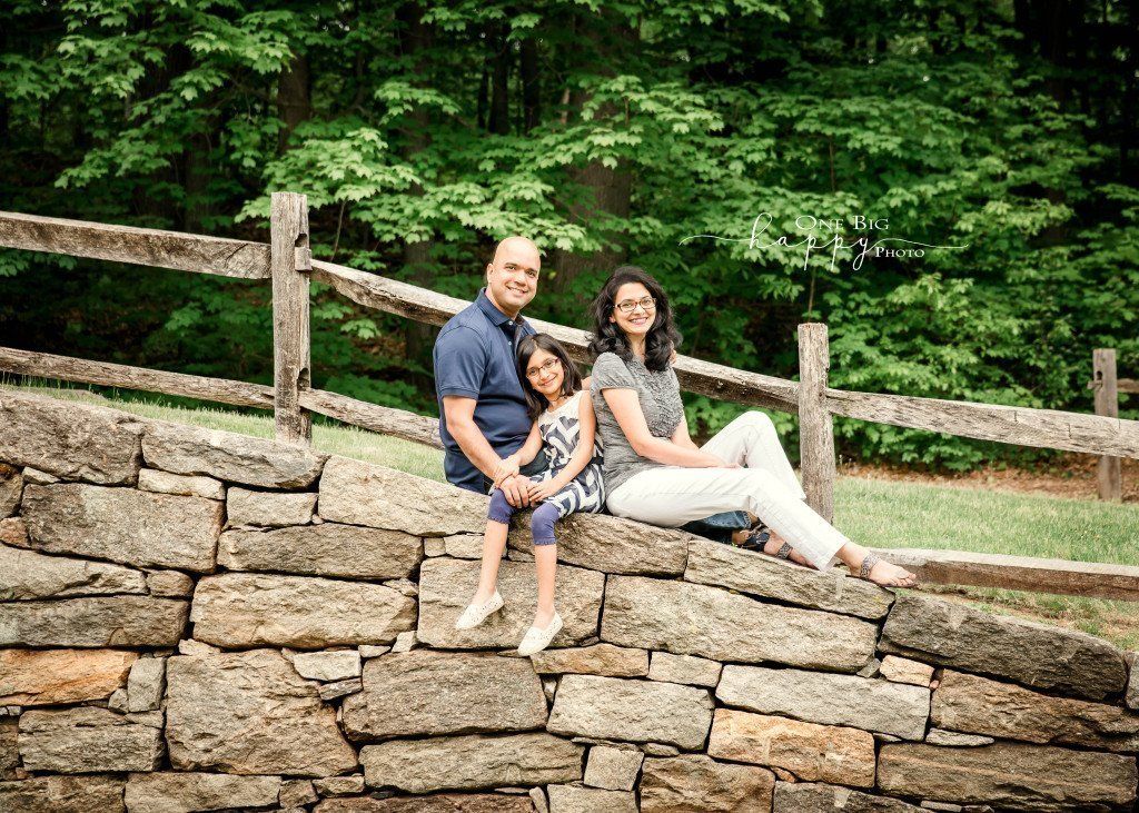 Mom Dad and daughter posing on a rock wall for portrait Mom Dad and daughter posing on a rock wall for portrait