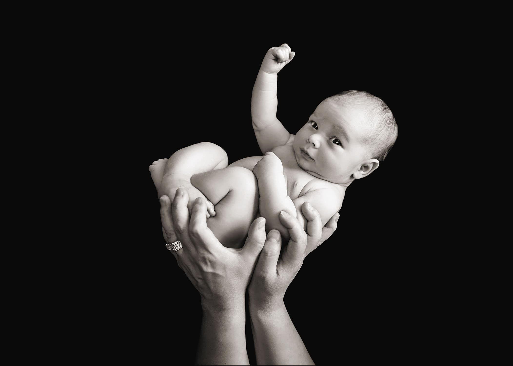 newborn son held up by mom's hands with his fist raised in the air Glastonbury CT Newborn Photographer One Big Happy Photo www.onebighappyphoto.com/newborns