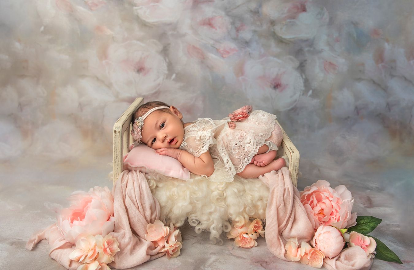 Newborn Photography CT awake newborn baby lying on a tiny bed surrounded by pink peonies