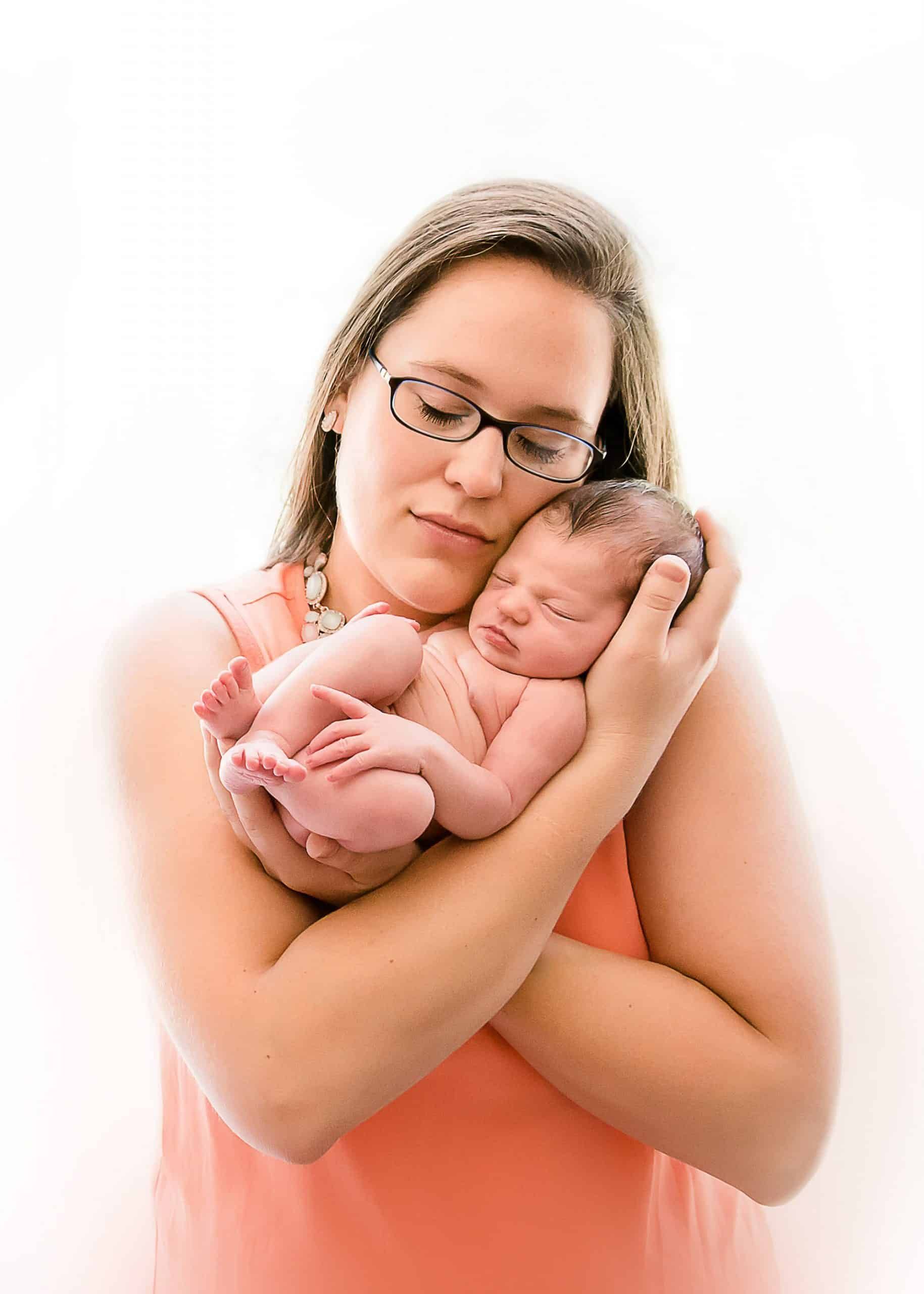 Mother cuddles her newborn baby under her chin