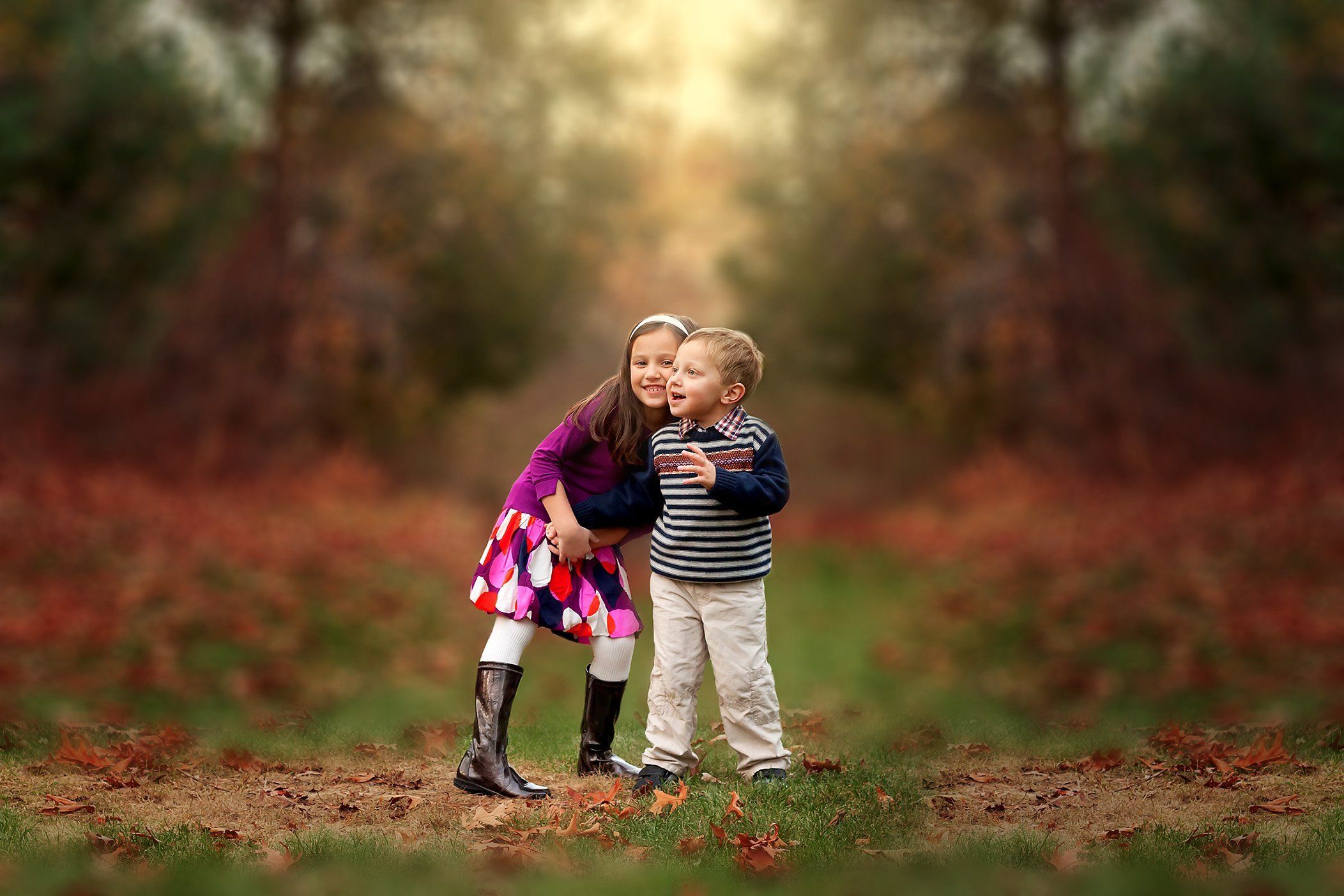 6 year old girl and 3 year old boy playing outside in the fall leaves