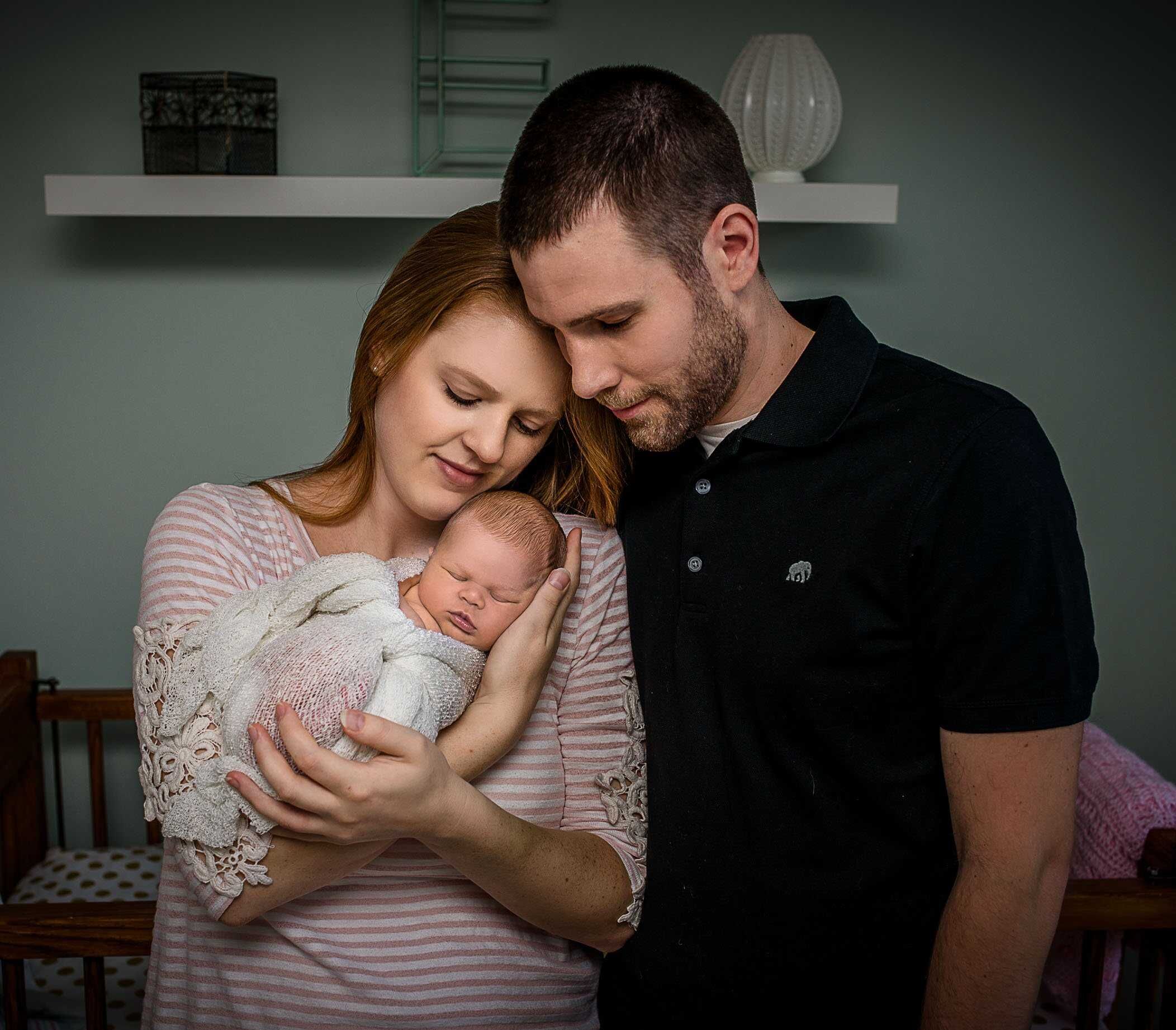 new parents holding sleeping newborn in mom's arms
