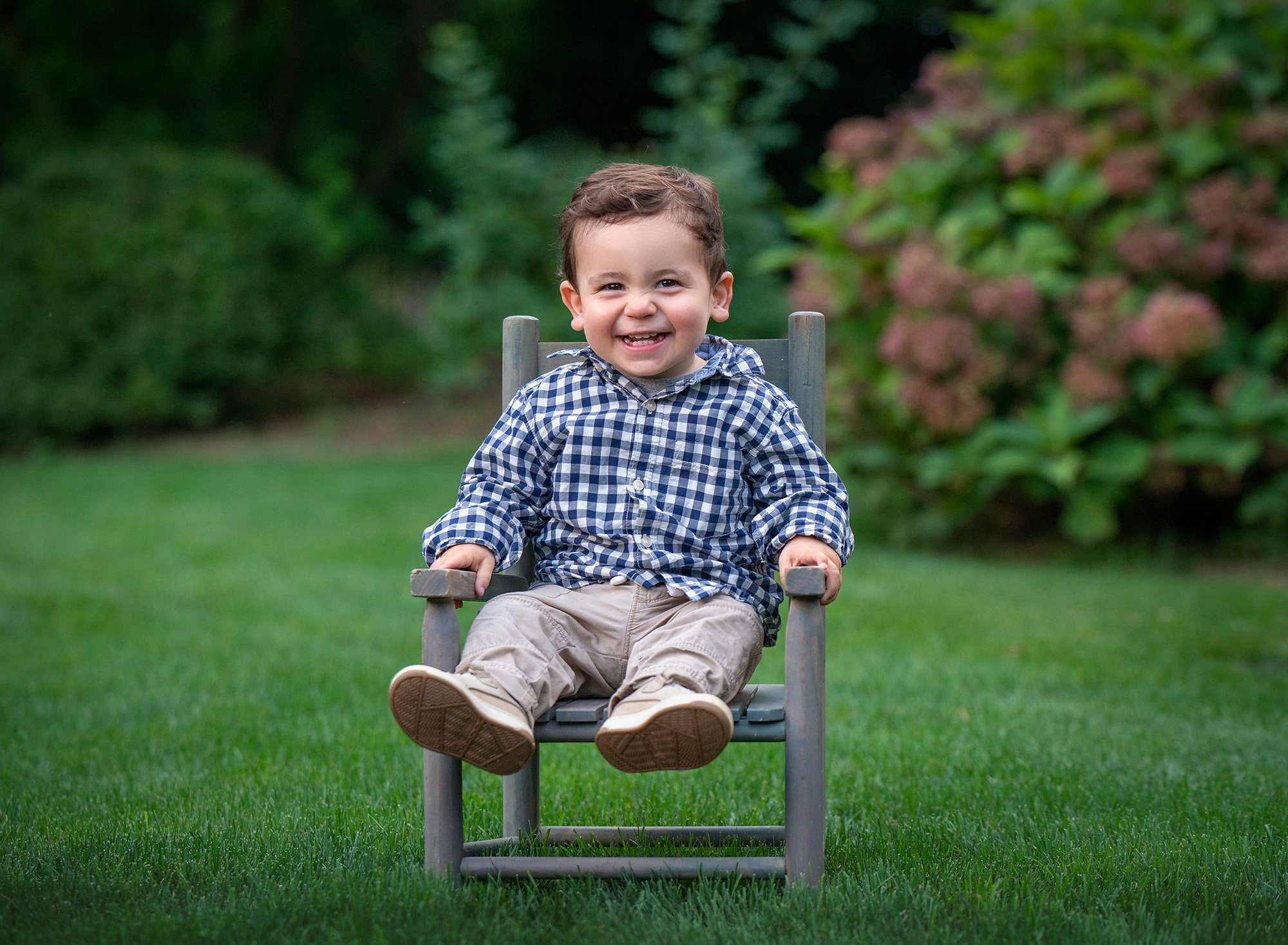 one year old boy in polo shirt sitting on a rustic chair in nature