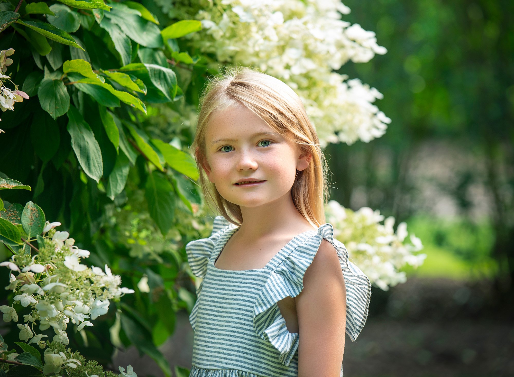 blonde haired little girl surrounded by white flowers
