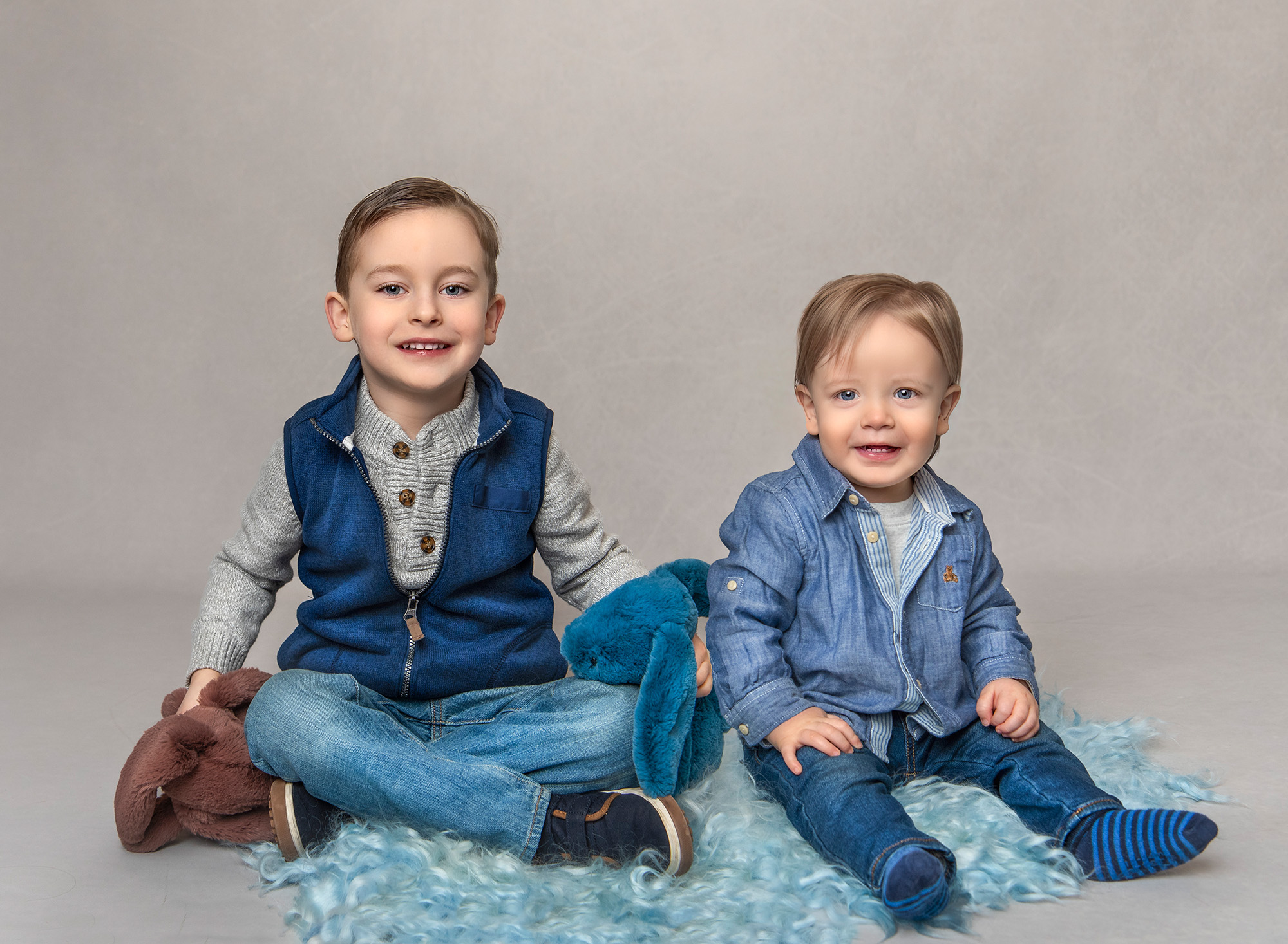 Bryce and Greyson sitting together on a blue ruffled carpet, smiling