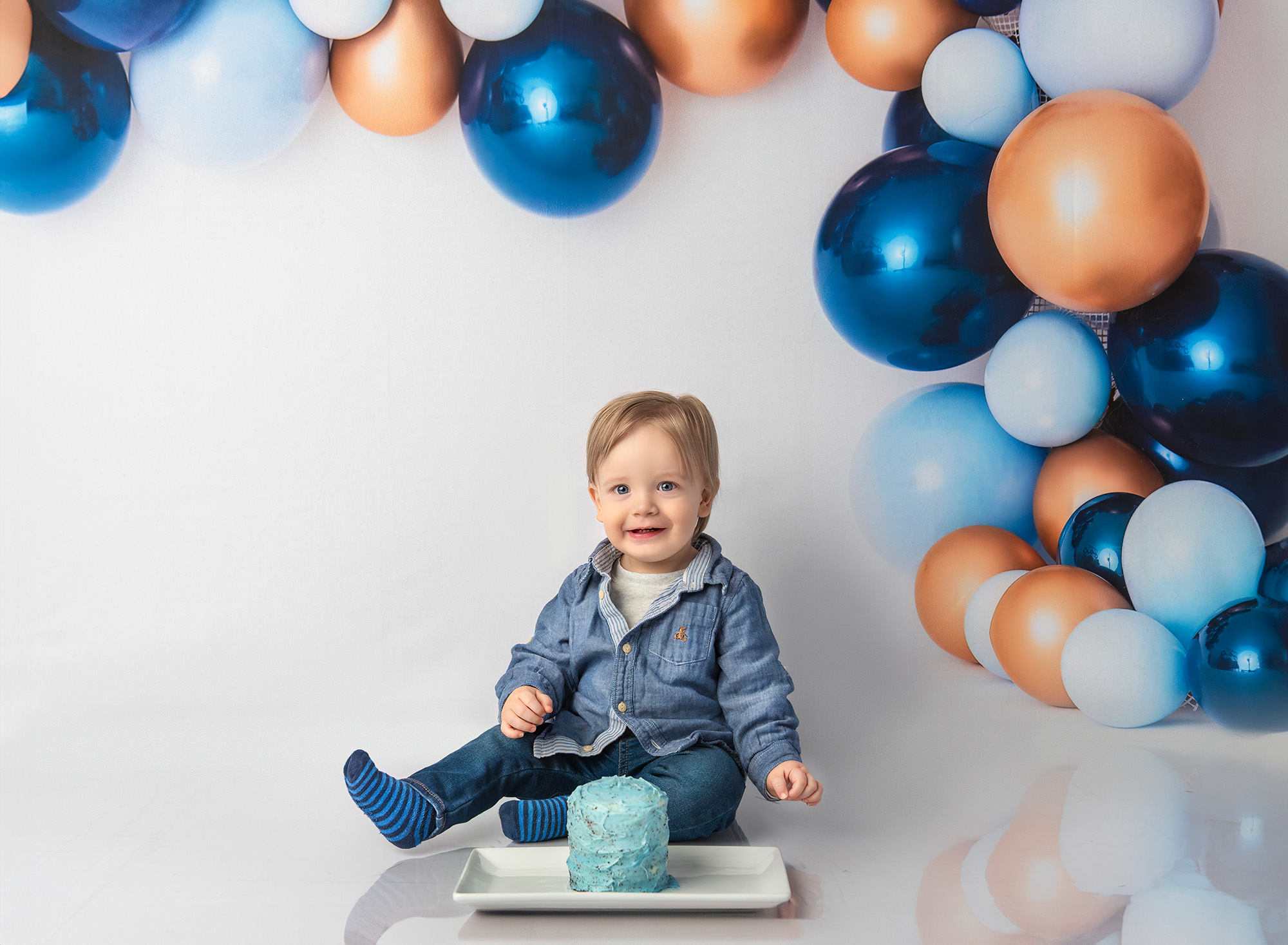 1st Birthday Photoshoot Bryce posing with his blue frosted birthday cake