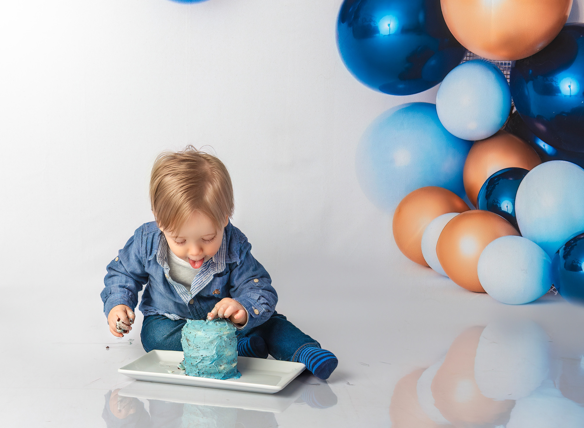 Bryce sticking out tongue while trying first birthday cake