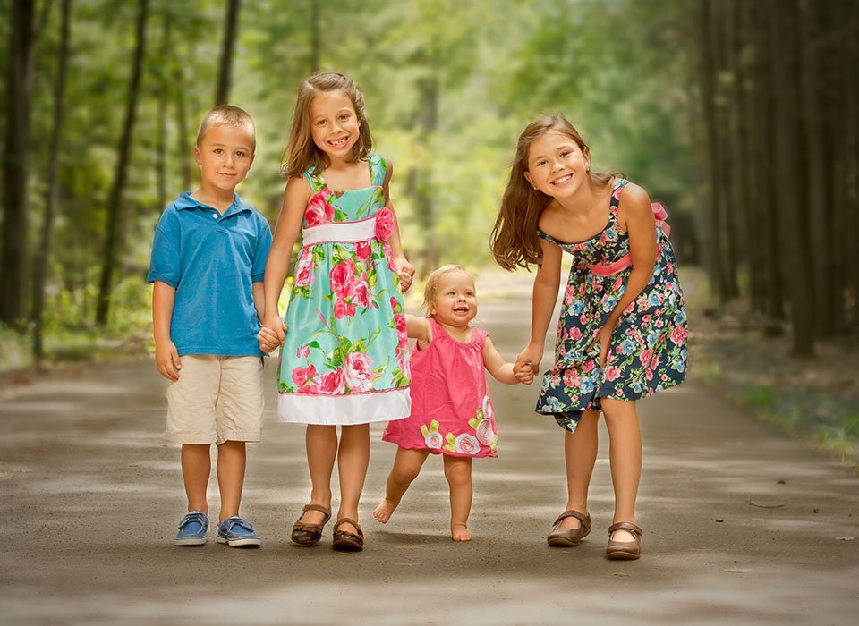 four young siblings taking a walk in the woods