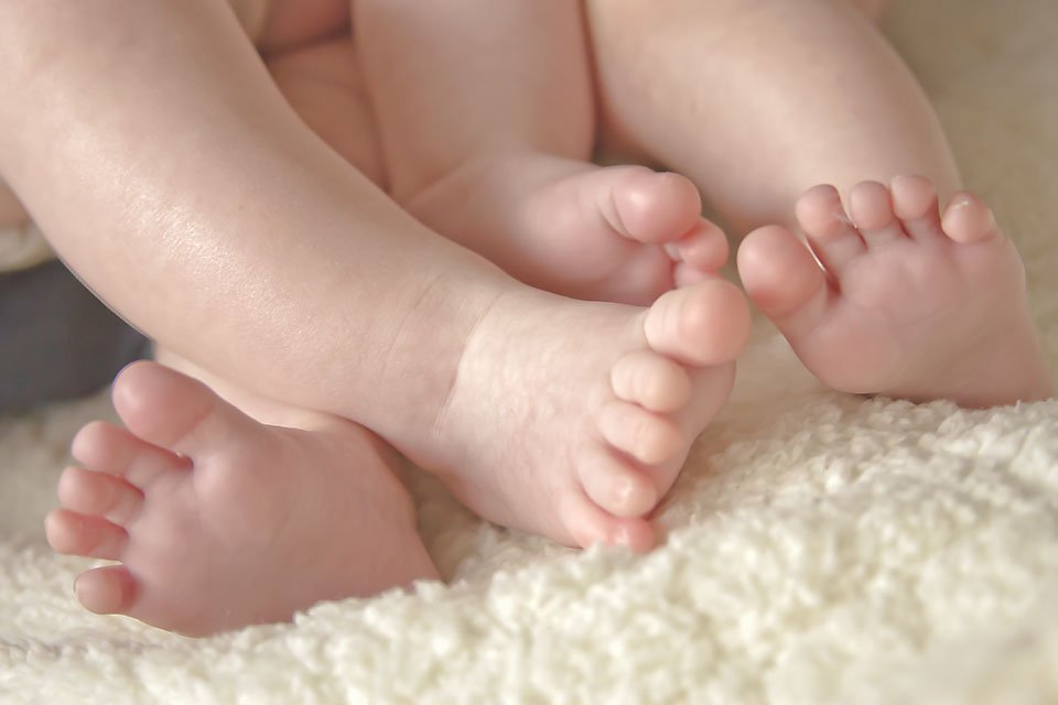 two little babies feet enter twined together