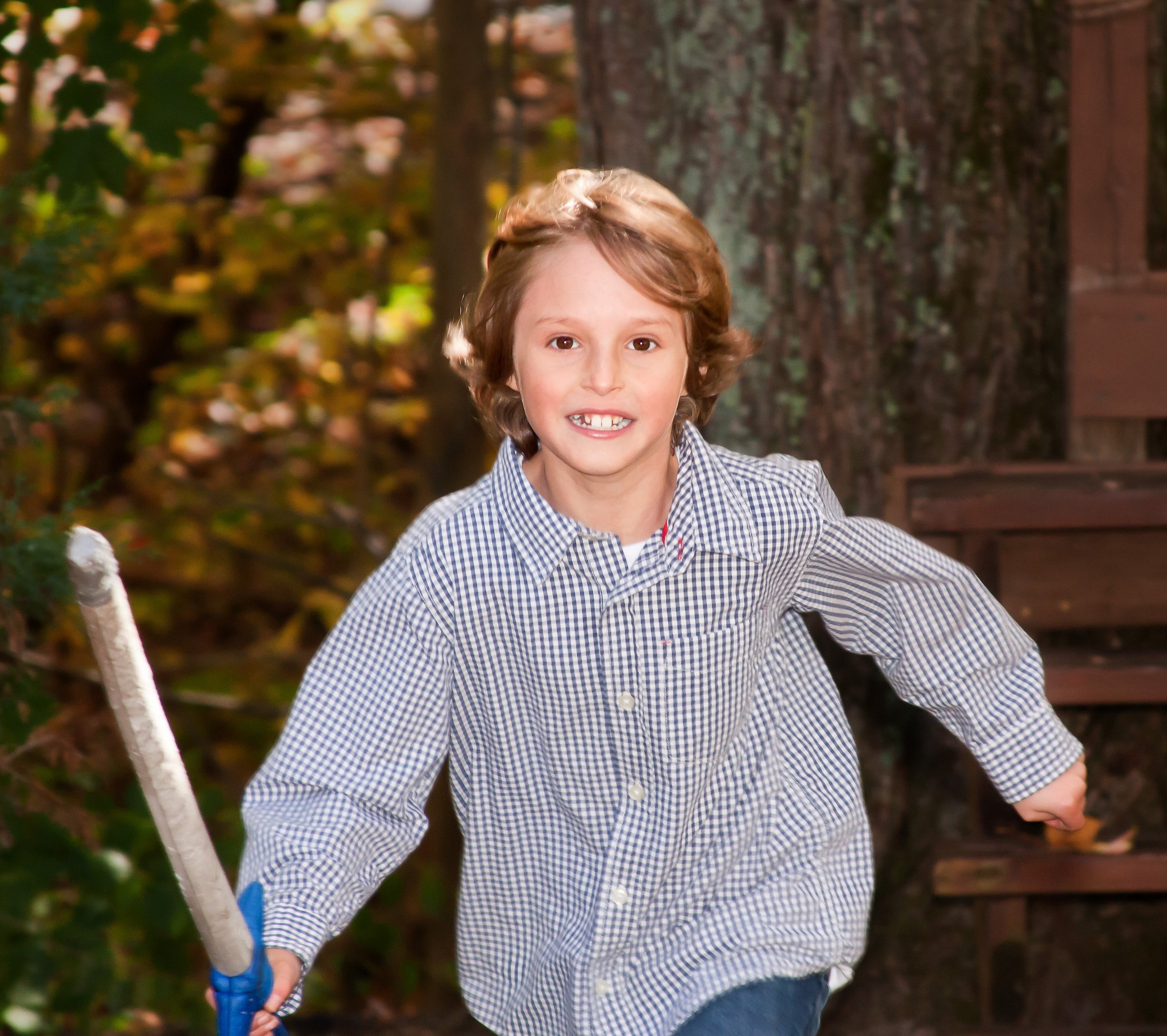 young boy caught mid action as he runs with a pretend sword towards a battle