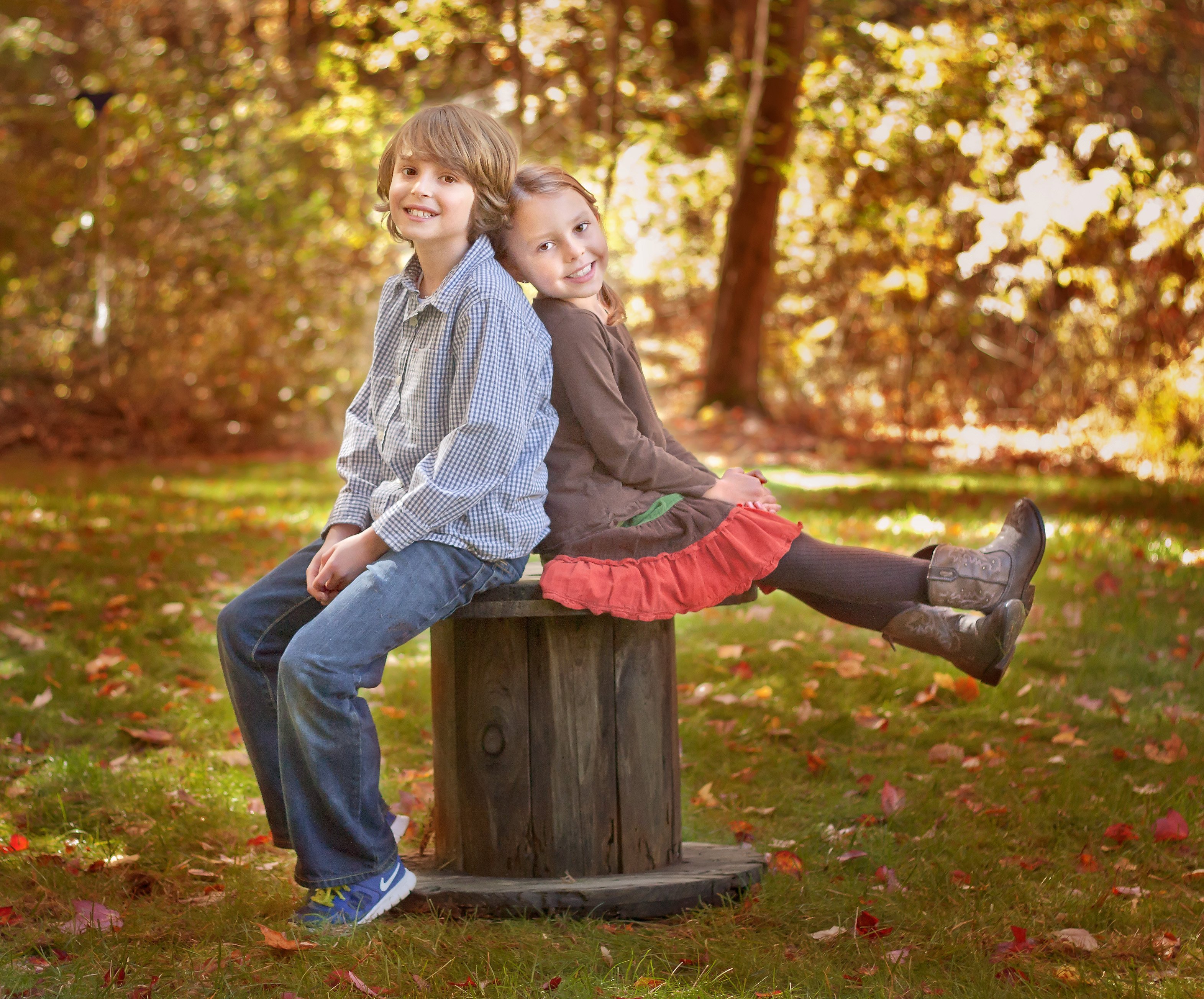 10 year-old son and 6-year old daughter posing on a spool in the fall