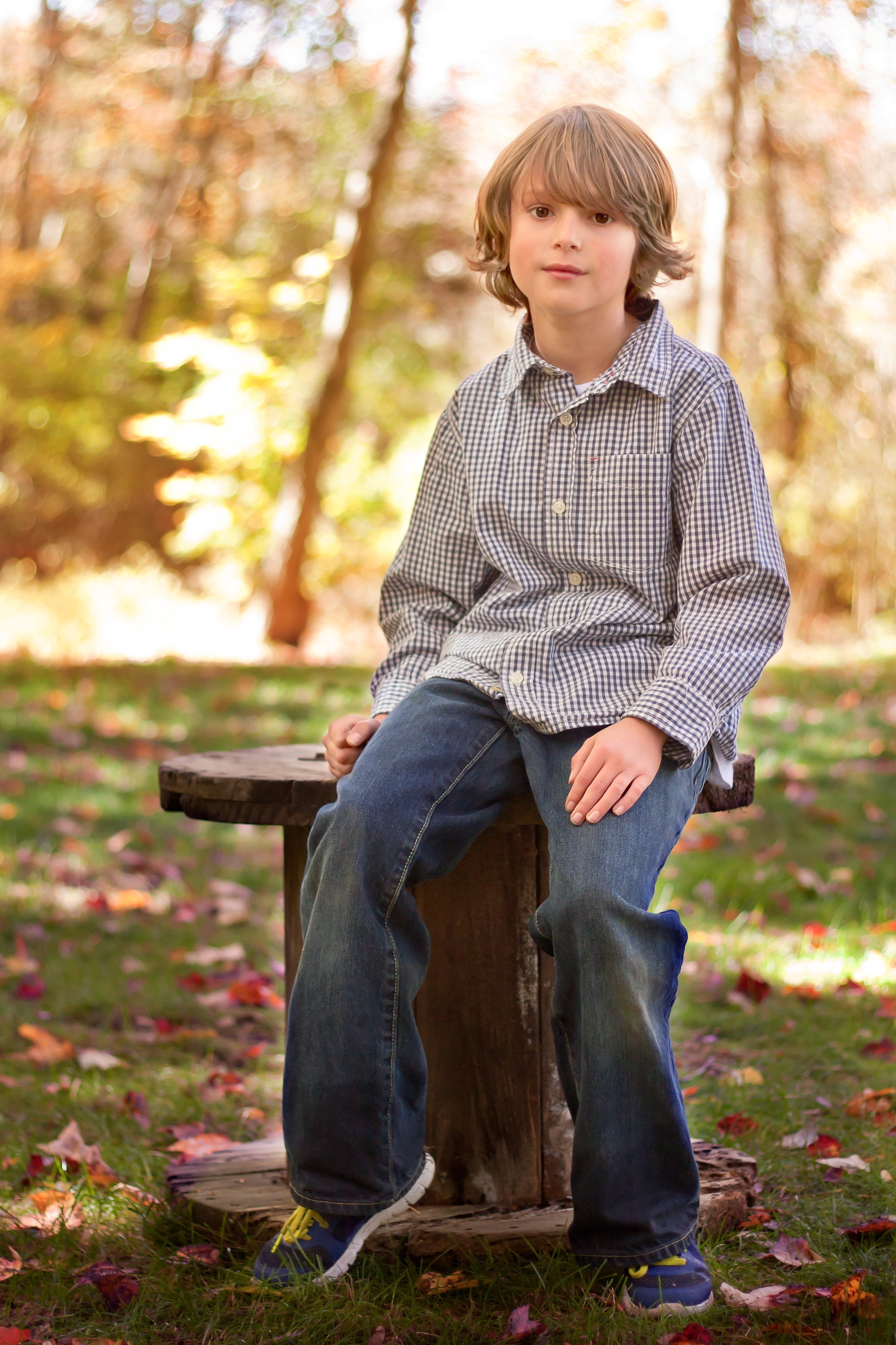 young boy sitting on a spool in the fall