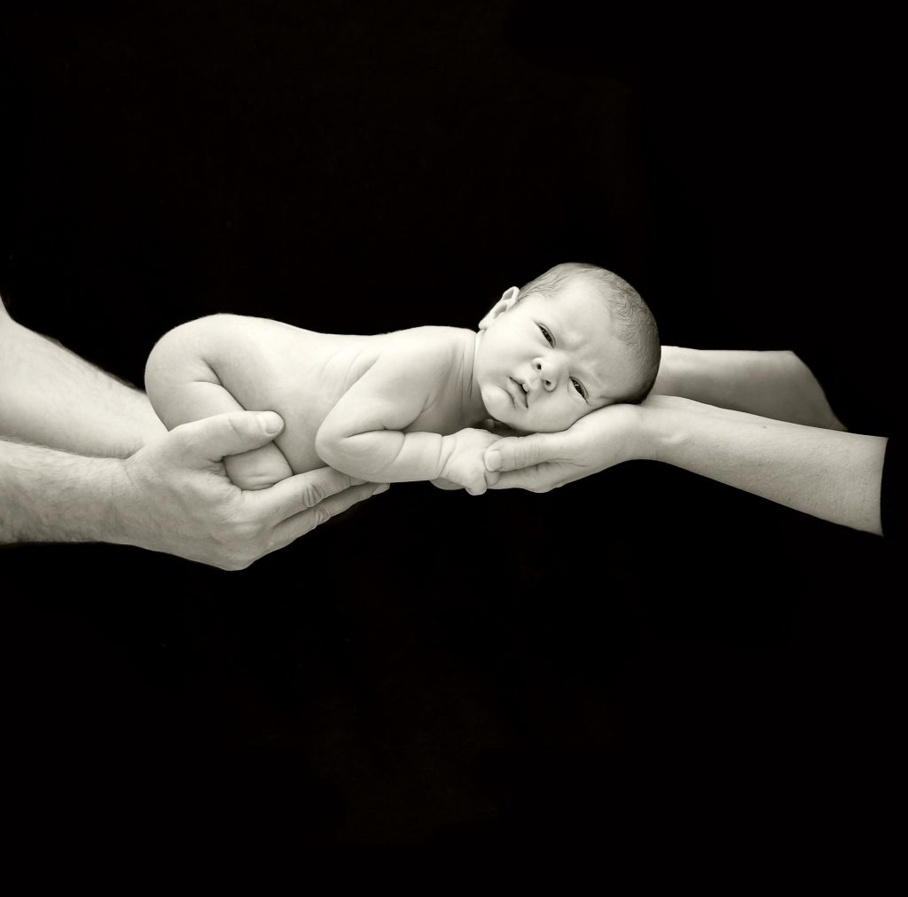 6 day old newborn boy being cradled in mom and dads hands