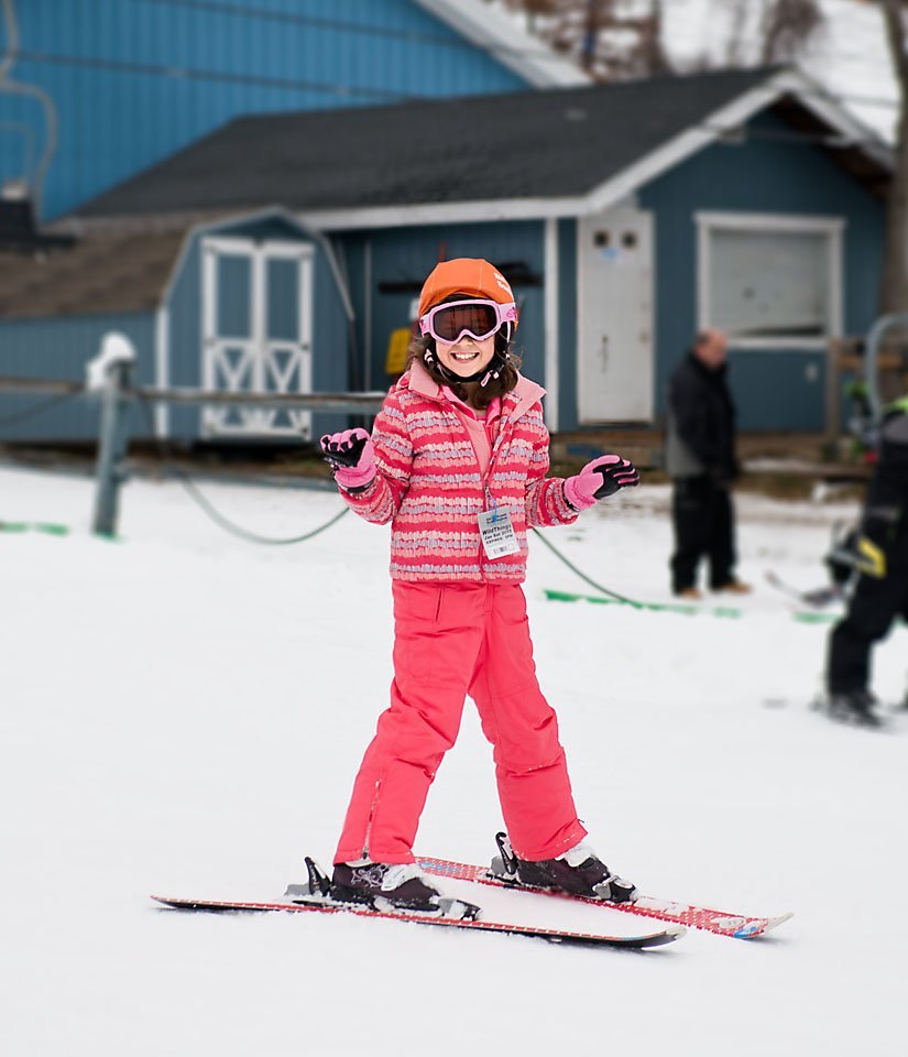 8 year old girl in bright pink skiing down a snow covered mountain