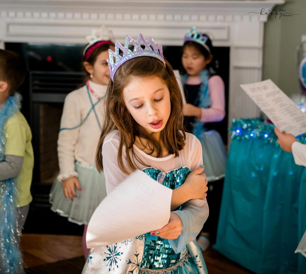 Little girl dressed up as Queen Elsa singing and hugging herself