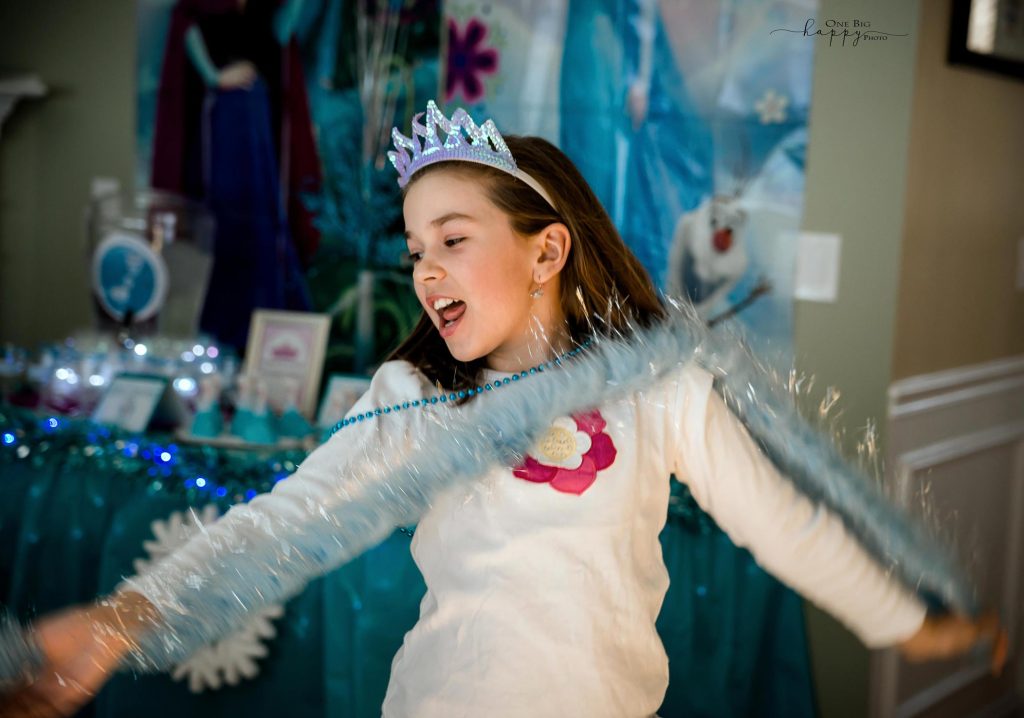 9 year old girl dancing with a blue boa on and a purple tiara