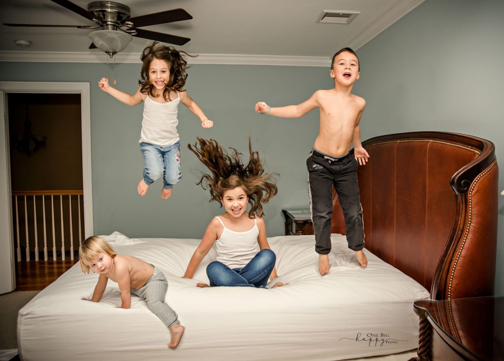 4 kids jumping on their parent bed