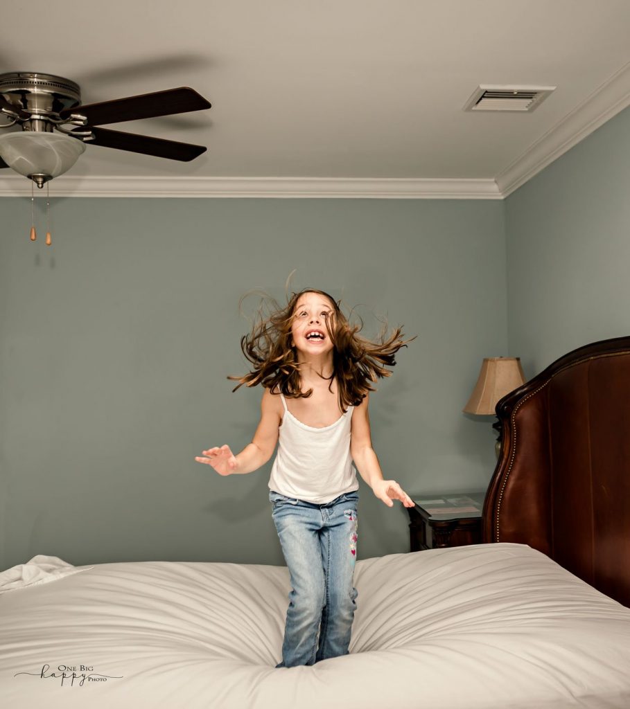 little girl jumping on her parents bed