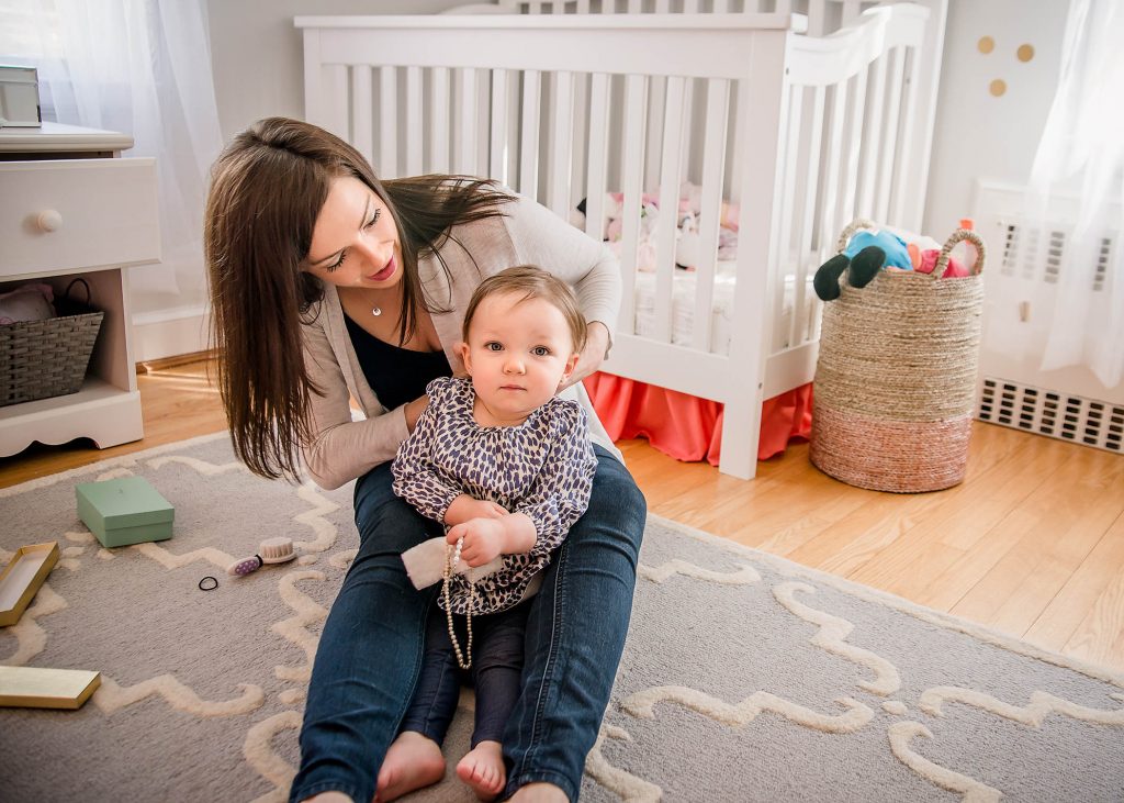 Mother helps toddler girl fix her hair and put on a necklace