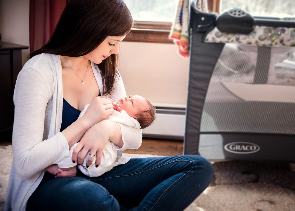 Mom and newborn girl look into each others eyes during a cuddle