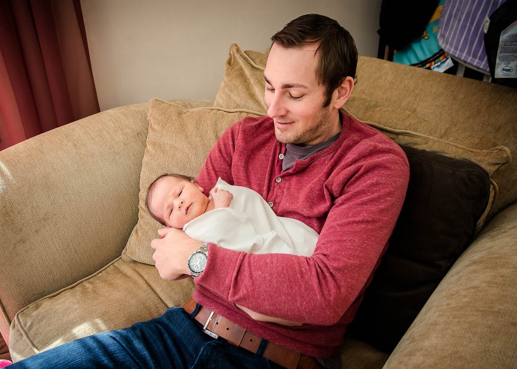 Dad holding his newborn daughter and smiling