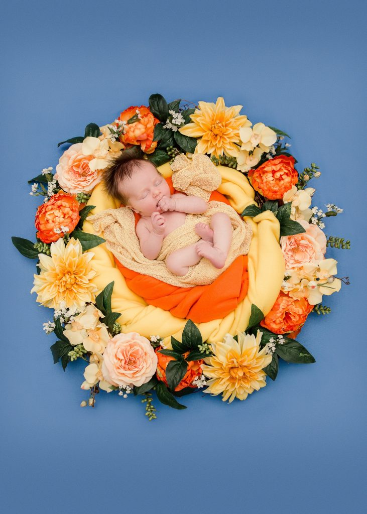 newborn lying in orange and yellow flower wreath