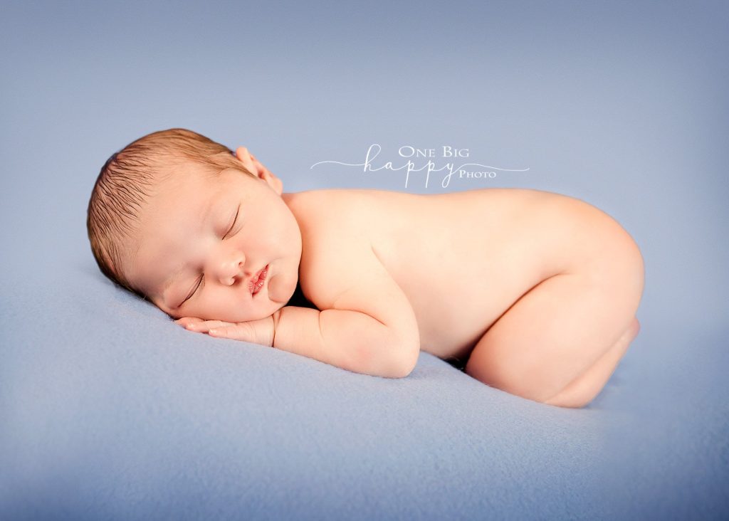 Newborn baby boy sleeping on blue blanket on tummy