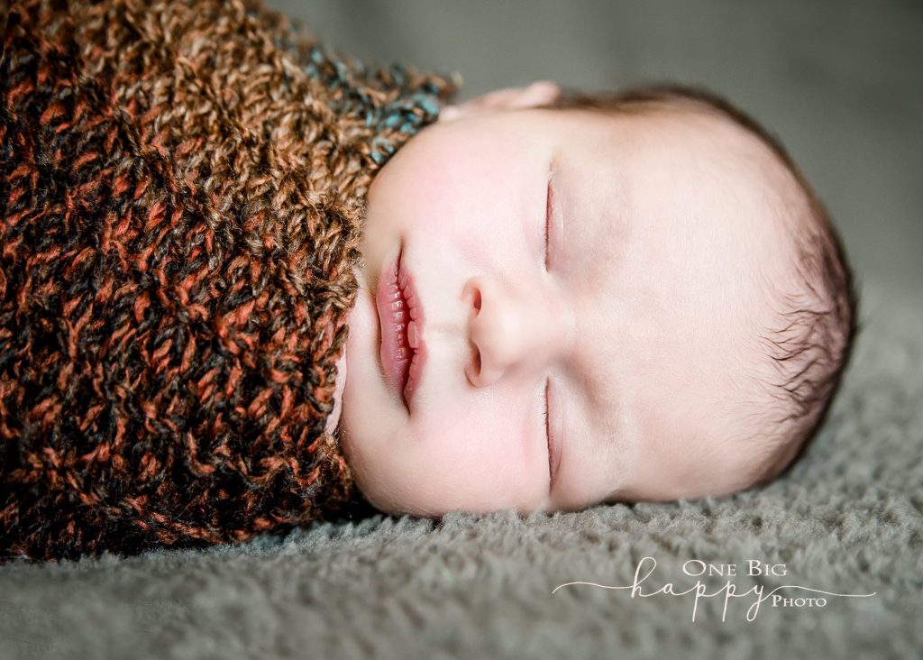newborn boy wrapped in fall colored knit scarf