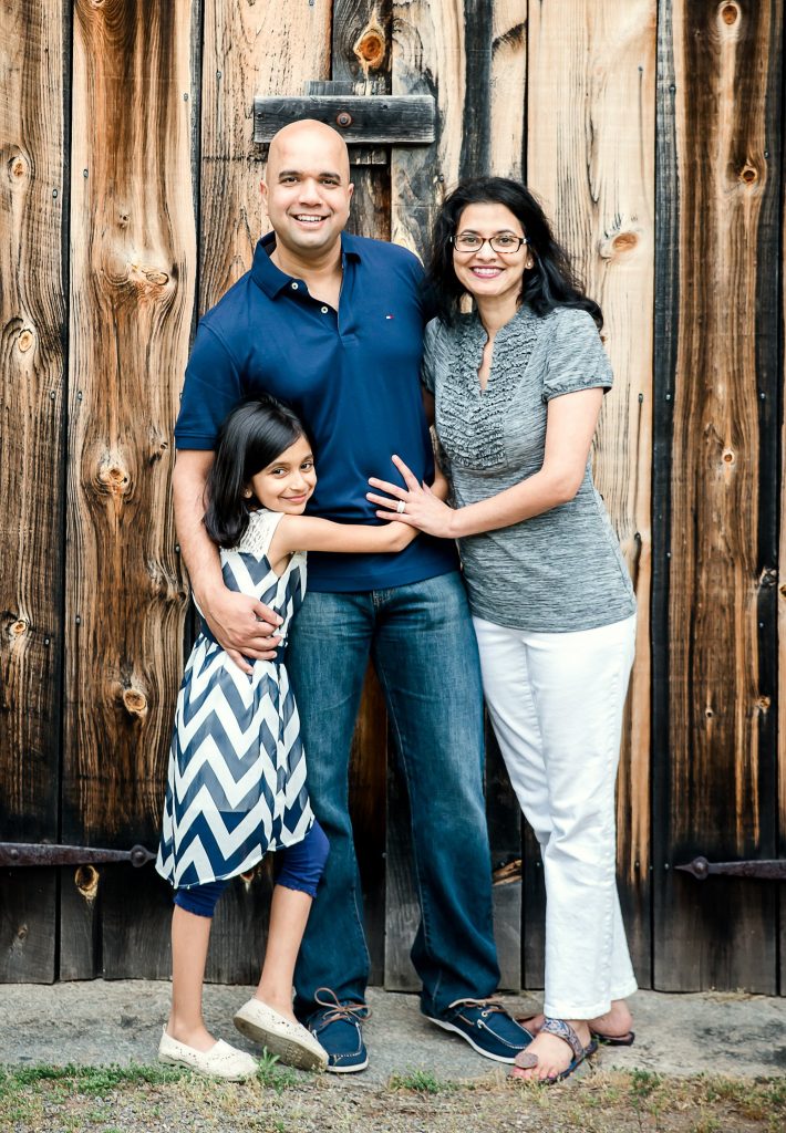 Family of 3 posed in front of a weathered barn door