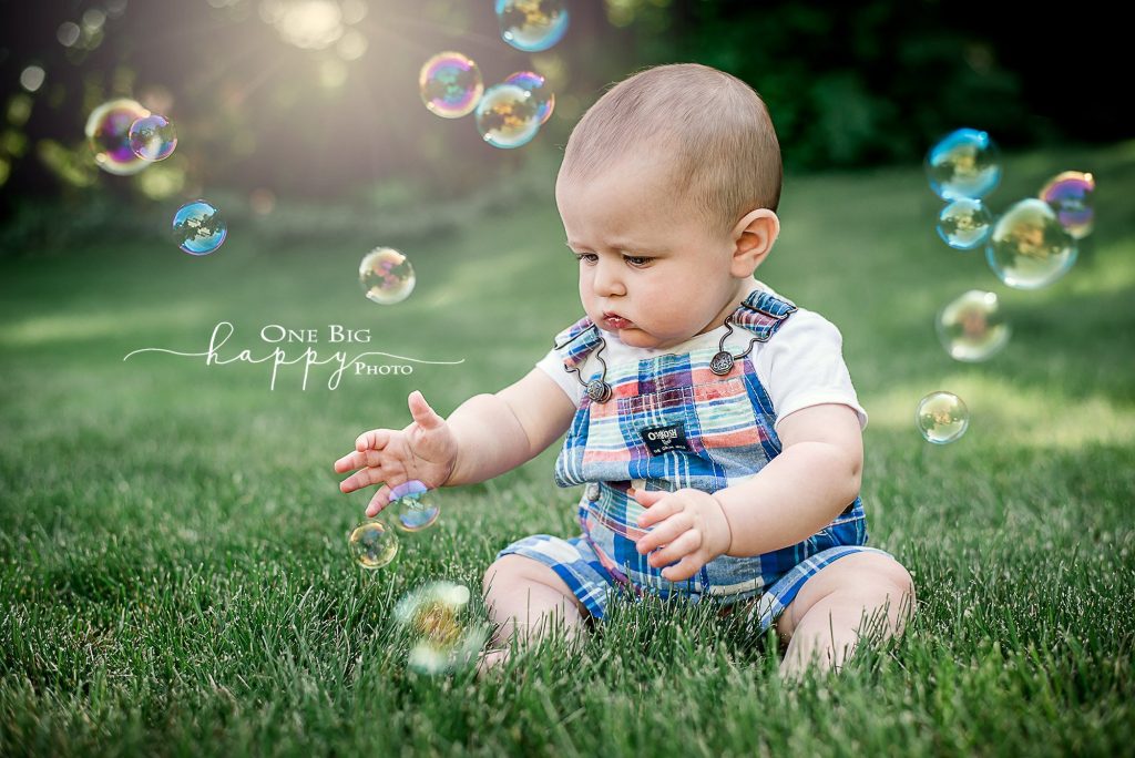 6 month old boy playing with bubbles on the lawn at dusk
