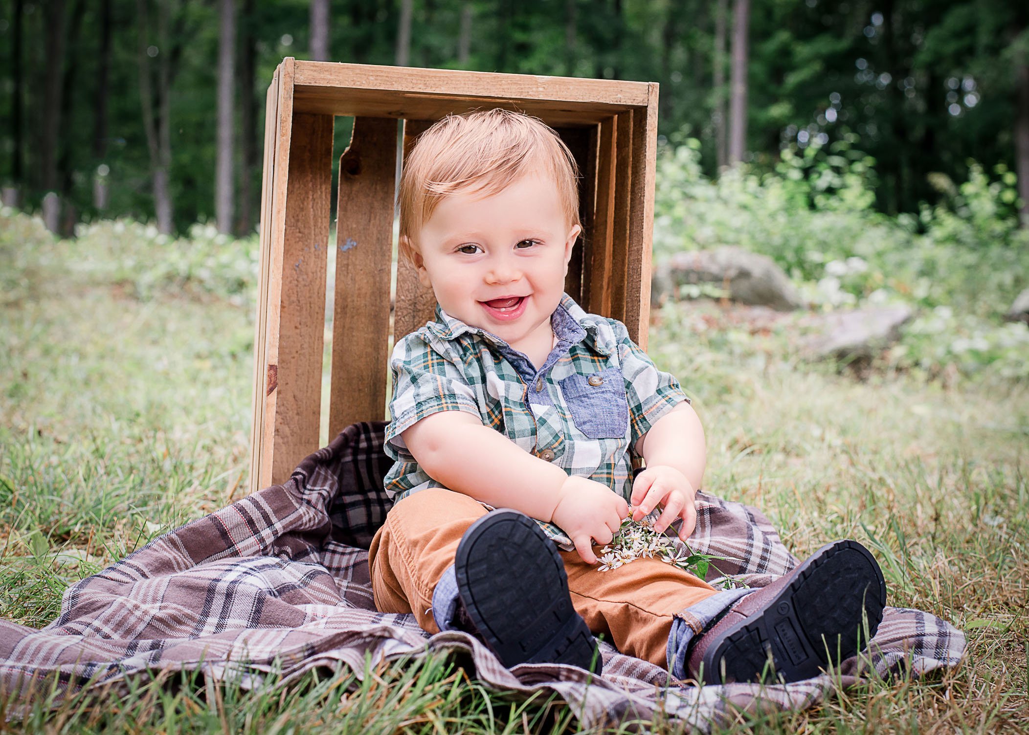 9 mo old baby boy sitting outside next to a wooden crate playing with flowers One Big Happy Photo