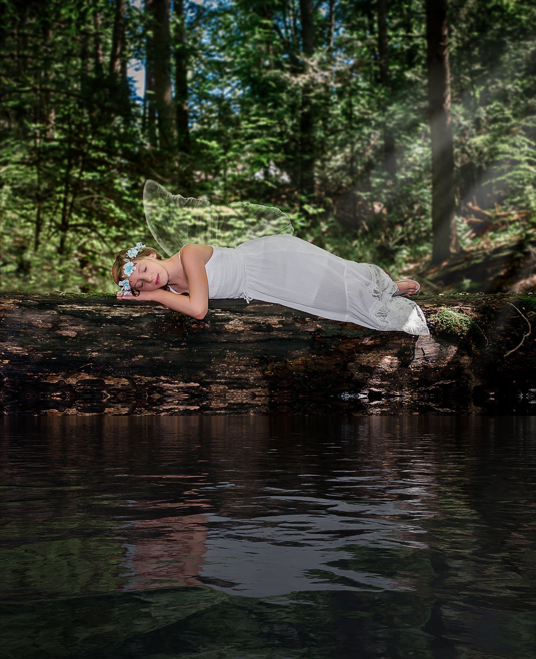 girl with fairy wings sleeping on log by pond One Big Happy Photo