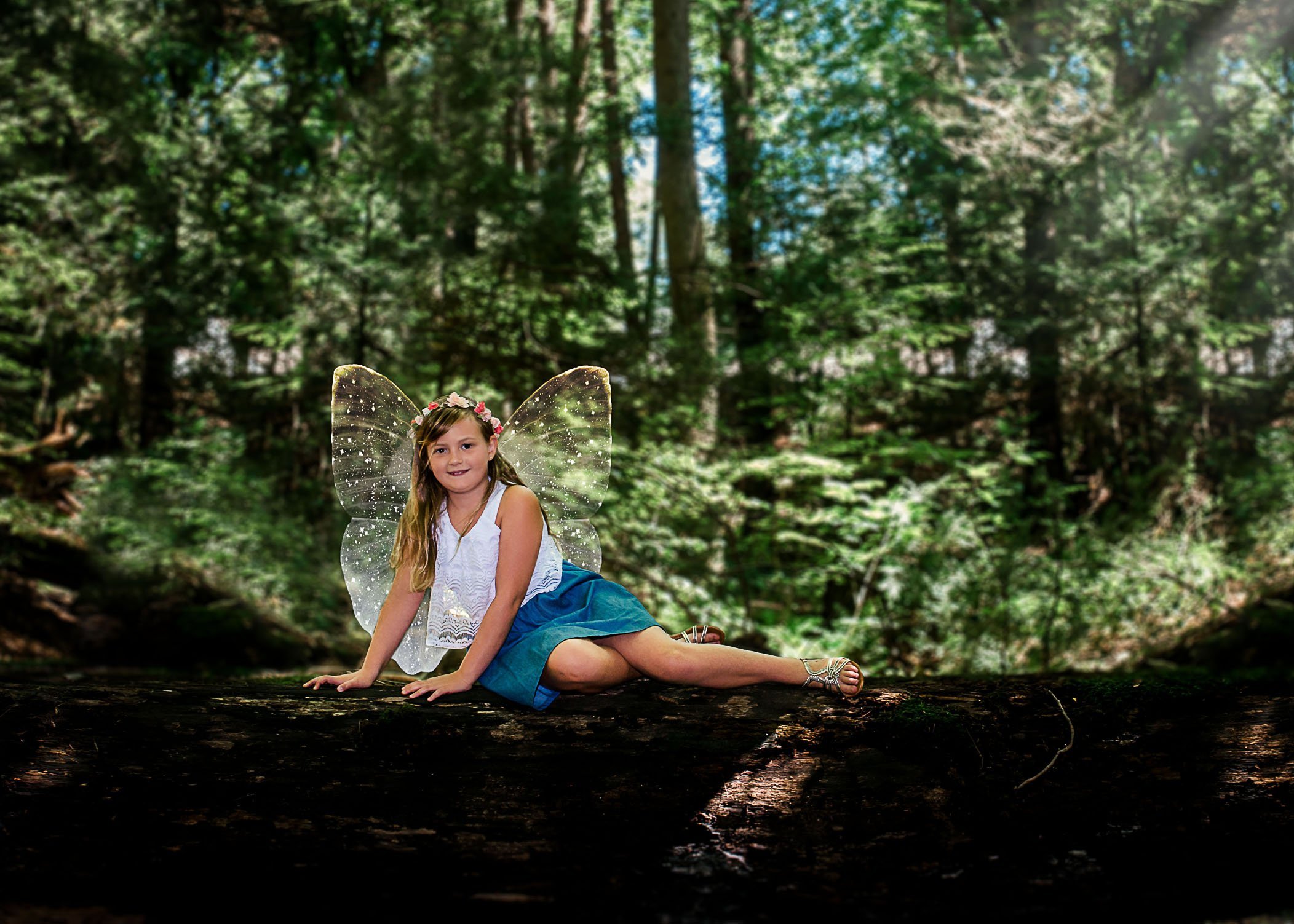 little girl with fairy wings lying on a log One Big Happy Photo