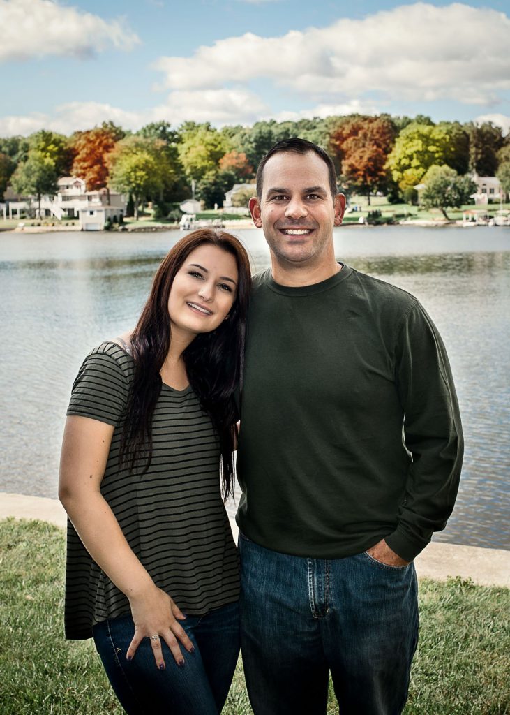 Dad and his adult daughter smiling in front of the lake in the fall One Big Happy Photo