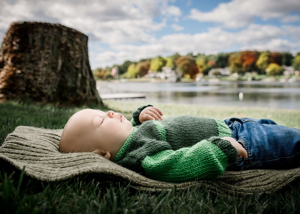sleeping 6 month old boy outside on a blanket next to a lake and fall foliage One Big Happy Photo
