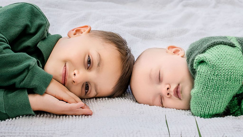 3 year old boy and his 6 month old brother resting on a blanket One Big Happy Photo