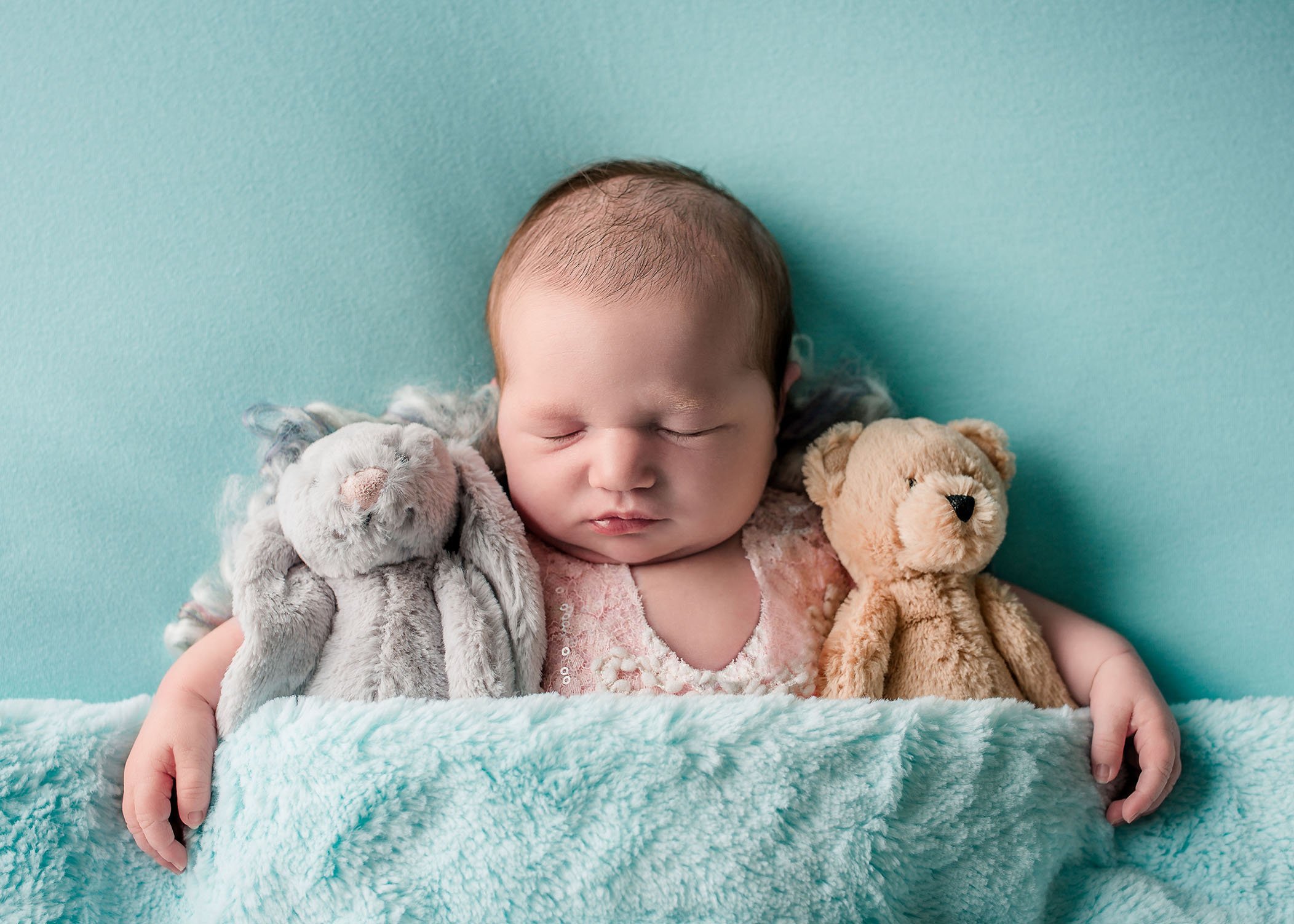 newborn baby girl sleeping on teal with her stuffed animals One Big Happy Photo