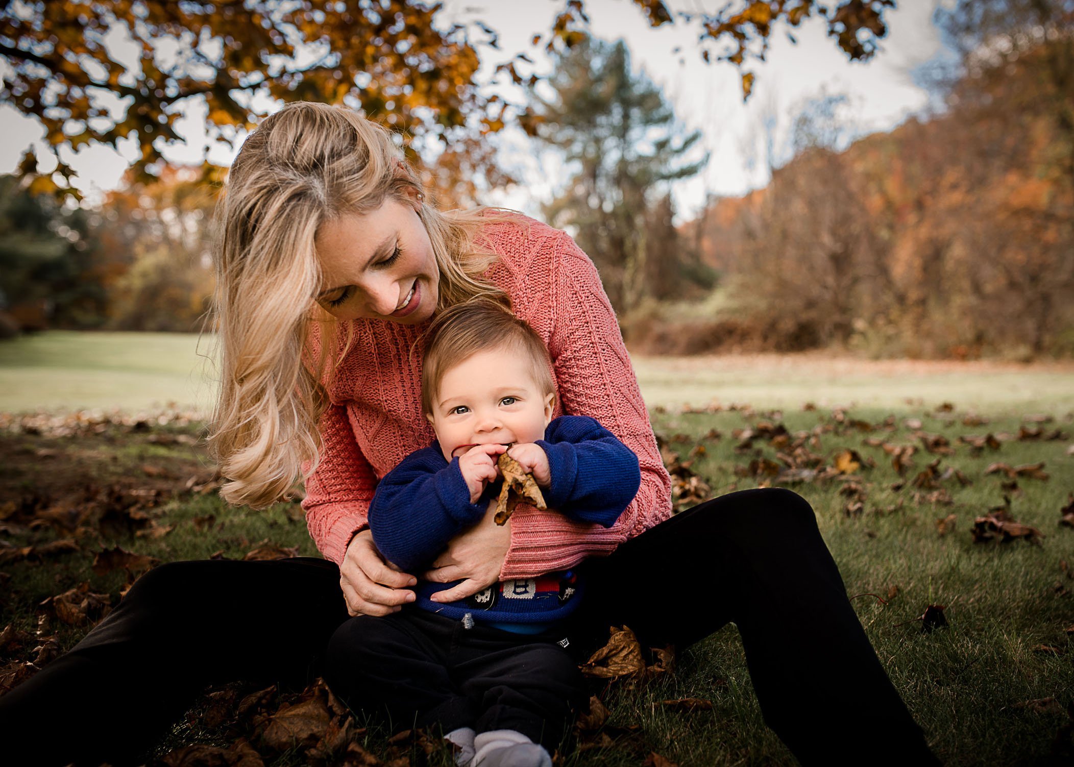 Mom playing with baby boy outside in fall leaves One Big Happy Photo