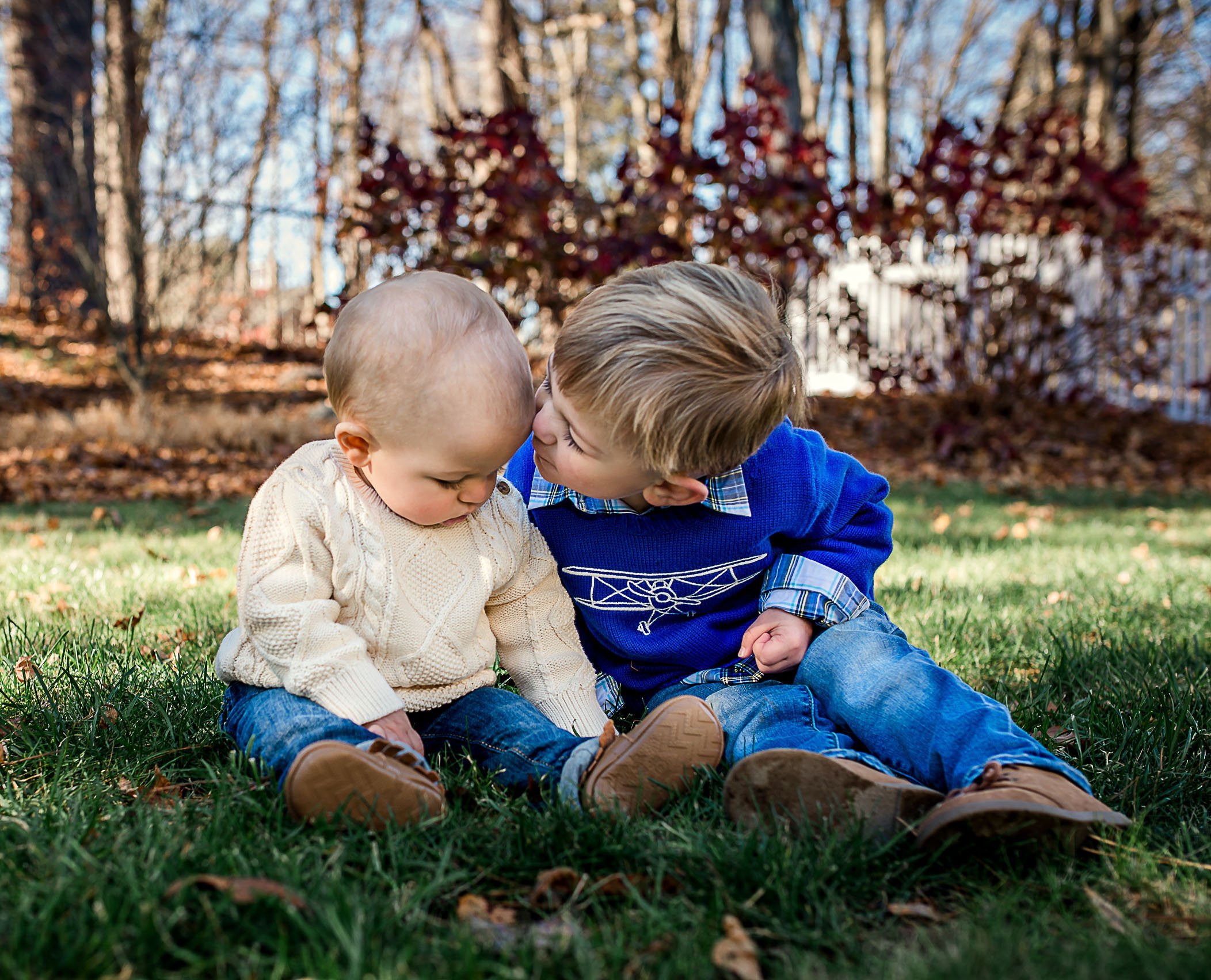 toddler kissing baby brother on the head in garden One Big Happy Photo