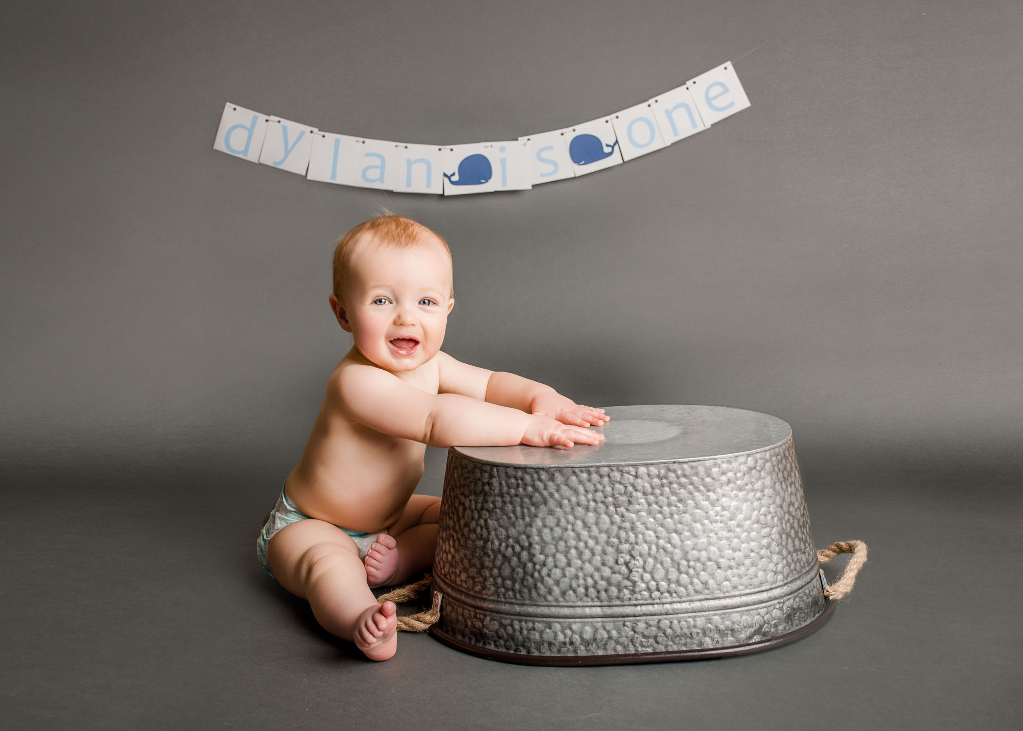 one year old baby banging on tin tub smiling One Big Happy Photo