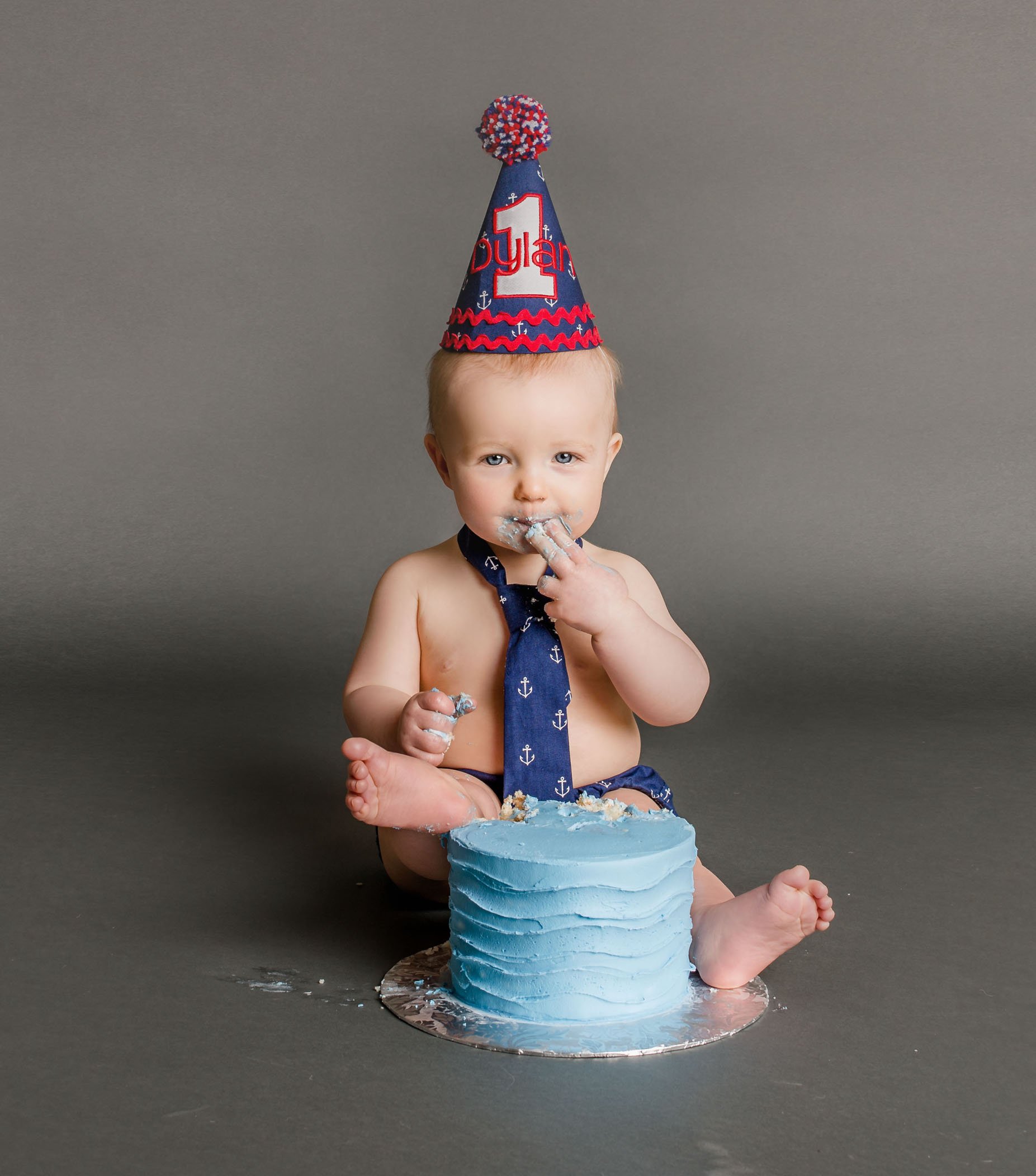 Baby tasting cake with fingers and feet in cake One Big Happy Photo