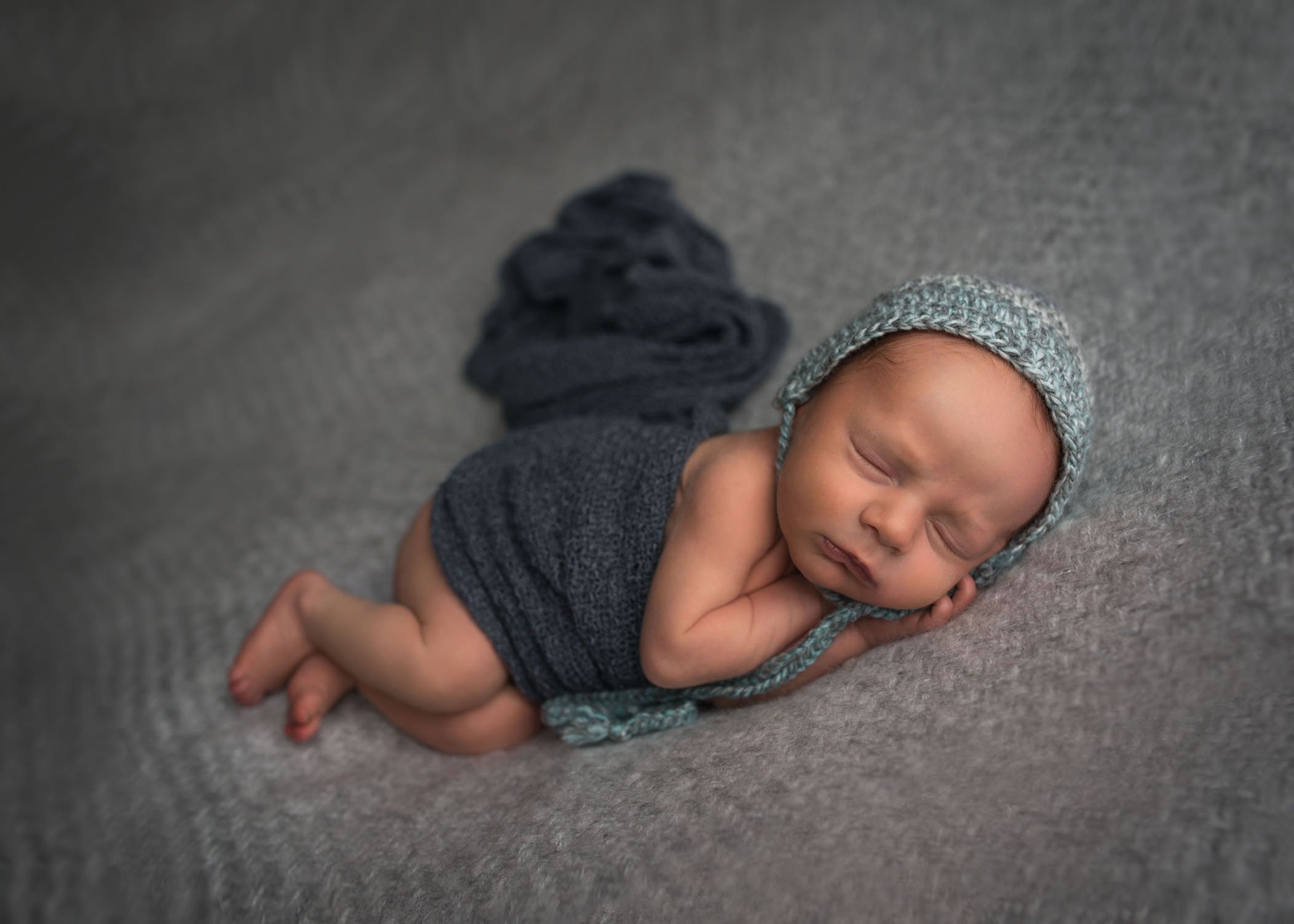 newborn sleeping on his side with cap and wrap on One Big Happy Photo